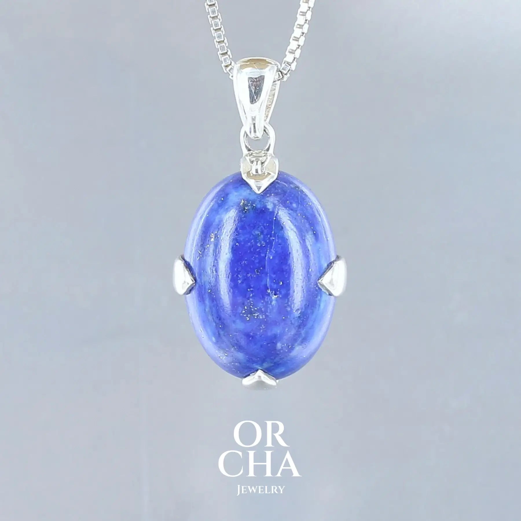 pendentif pour femme en argent massif serti d'un cabochon de Lapis lazuli de couleur bleu nuit moucheté d'éclats dorés de Pyrite. Pierre naturelle opaque. Bijoux unique, éthique et durable présenté dans un coffret de notre marque, prêt à offrir. Livraison offerte, certificat d'authenticité, service client.