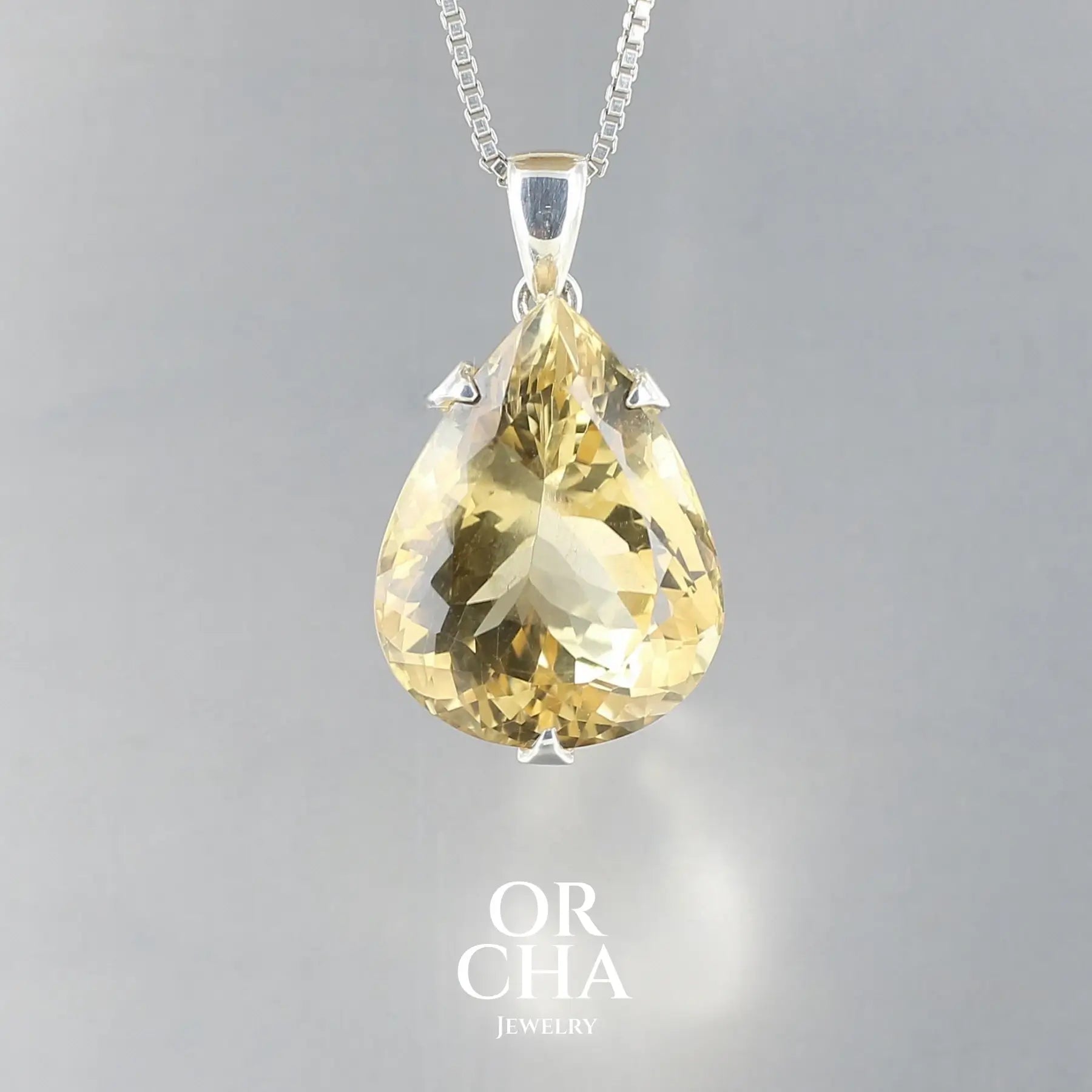 Grand pendentif pour femme en argent massif serti d'une Citrine de couleur jaune clair doré, lumineuse. Pierre facettée en forme de goutte, transparente, propre à l'oeil. Pierre ayant subit un traitement de chauffe, traitement admis et fréquent en gemmologie pour ce type de pierre . Bijoux unique, éthique et durable présenté dans un coffret de notre marque, prêt à offrir. Livraison offerte, certificat d'authenticité, service client.