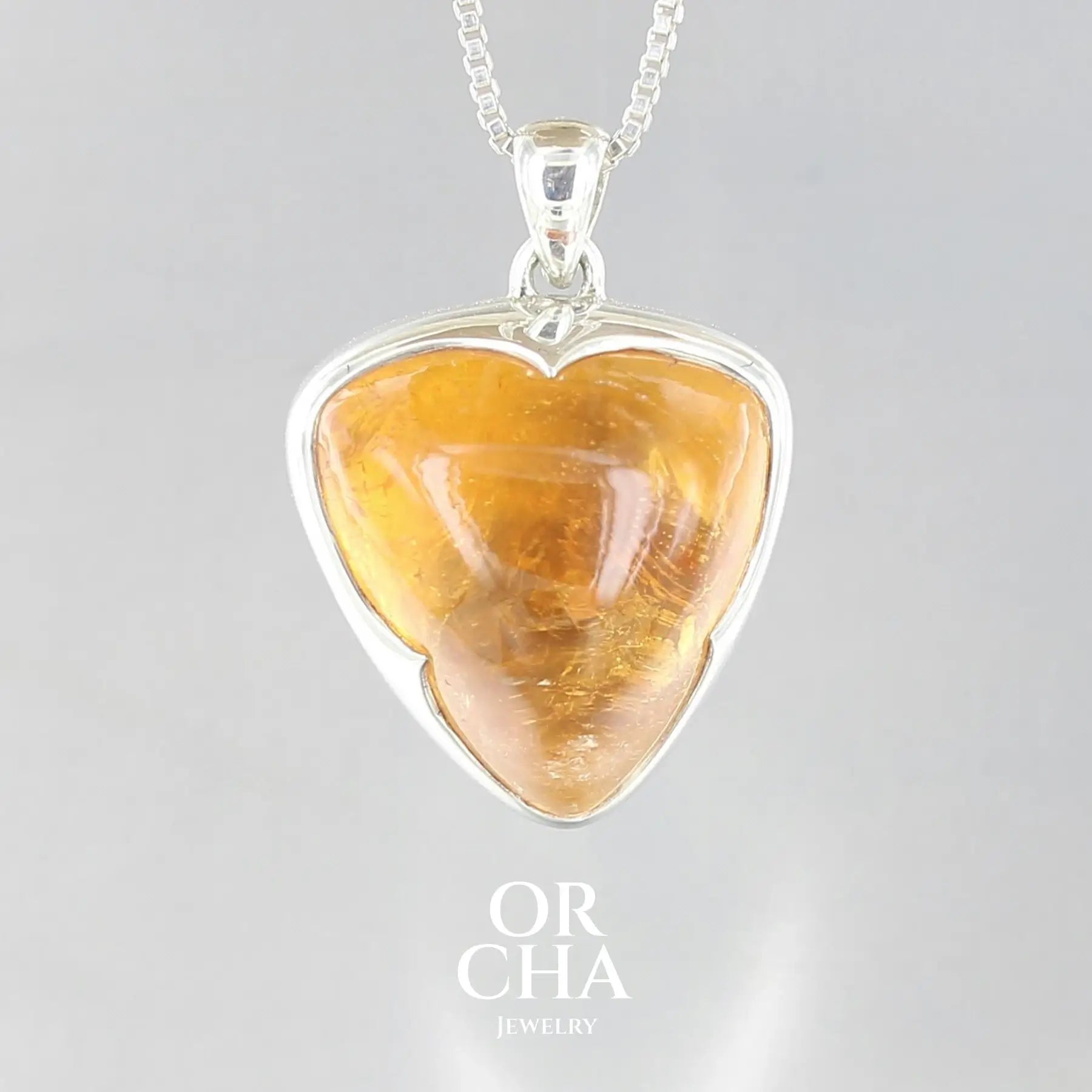 pendentif pour femme en argent massif serti d'une Citrine de couleur jaune doré miel intense. Pierre cabochon transparente présentant des inclusions. Pierre ayant subit un traitement de chauffe, traitement admis et fréquent en gemmologie pour ce type de pierre . Bijoux unique, éthique et durable présenté dans un coffret de notre marque, prêt à offrir. Livraison offerte, certificat d'authenticité, service client.