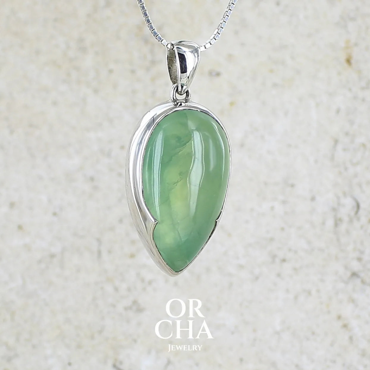 Pendentif pour femme en argent massif serti d'une préhnite de couleur vert jaune clair. Pierre naturelle taillée en cabochon en forme de goutte. Bijoux unique par orchajewelry.