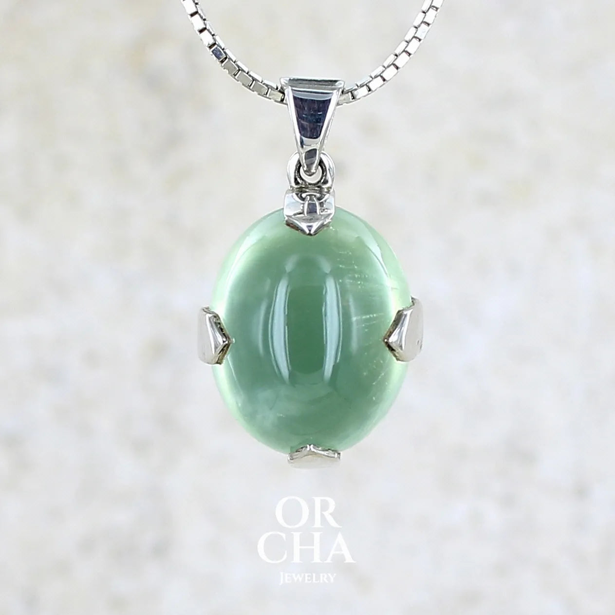 Pendentif ovale en argent massif, serti d'un cabochon de préhnite de couleur verte clair. Pierre de qualité translucide comportant des inclusions. Bijoux unique par Orcha Jewelry