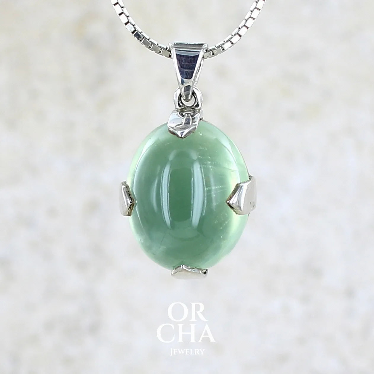 Pendentif ovale en argent massif, serti d'un cabochon de préhnite de couleur verte clair. Pierre de qualité translucide comportant des inclusions. Bijoux unique par Orcha Jewelry
