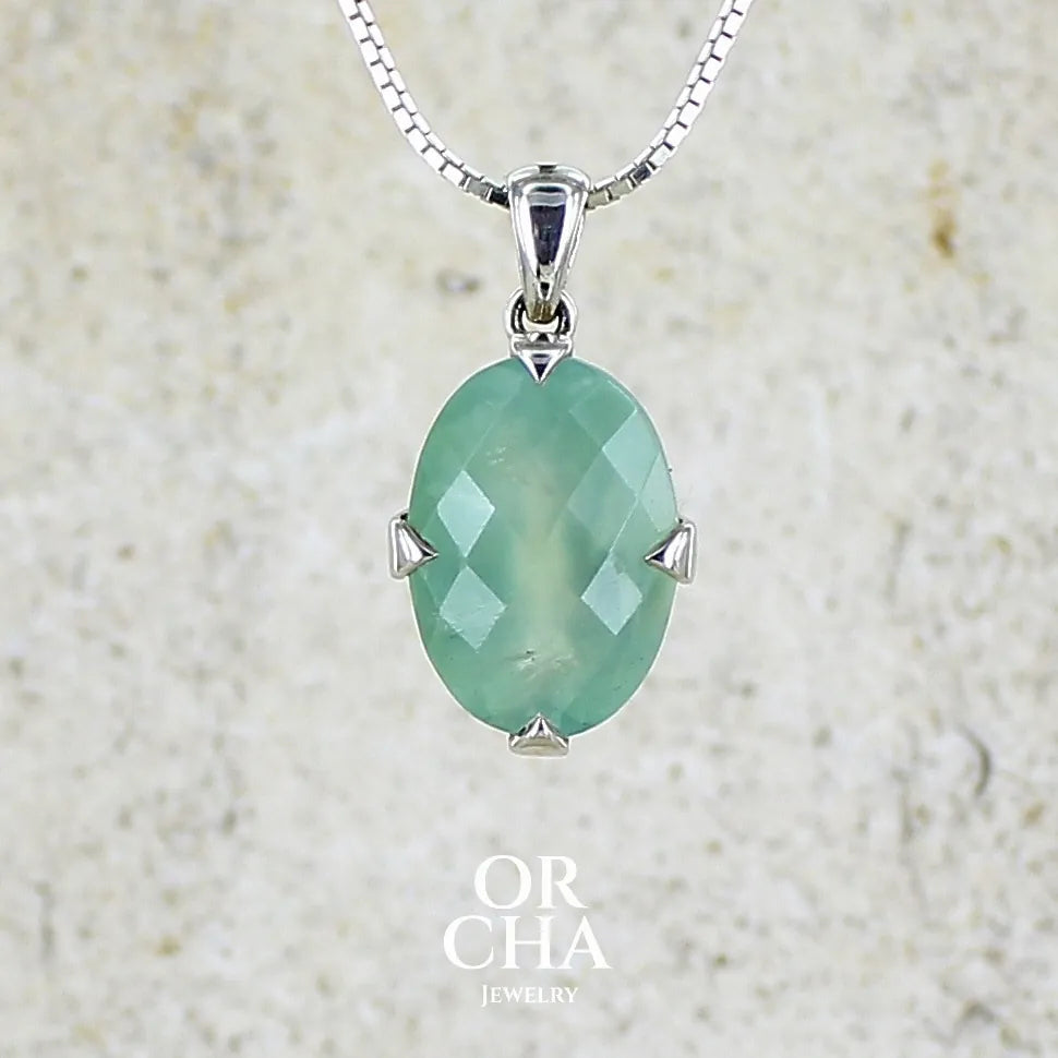 Pendentif ovale en argent massif, serti d'un cabochon facetté de préhnite de couleur bleue verte. Pierre de qualité translucide comportant des inclusions. blanches. Bijoux unique par Orcha Jewelry