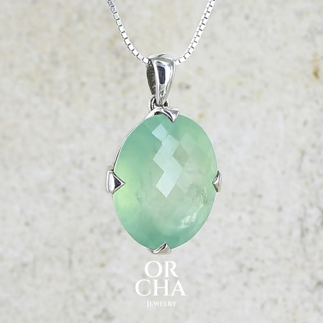 Pendentif ovale en argent massif, serti d'un cabochon facetté de préhnite de couleur verte pastel. Pierre de qualité translucide comportant des inclusions. Bijoux unique par Orcha Jewelry