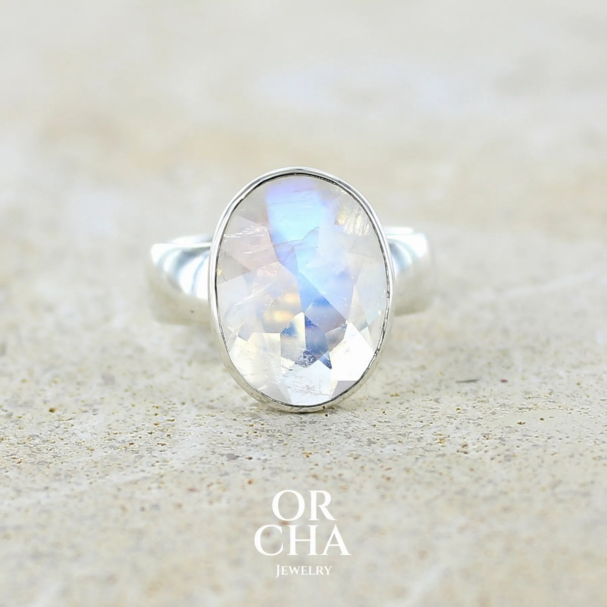 Bague cocktail pour femme en argent massif 925 sertie d'une Labradorite blanche taillée de 6,7 carats incolore aux reflets bleutés et arc en ciel. Pierre transparente avec inclusions. Bijoux unique réalisée en taille 57 par Orchajewelry