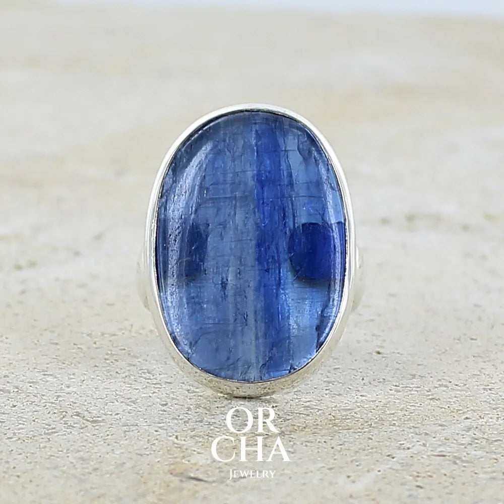 Bague pour femme en argent massif, sertie d'un cabochon de cyanite de couleur bleue denim. Pierre transparente de forme ovale. Bijou unique réalisée en taille 52 par Orchajewelry