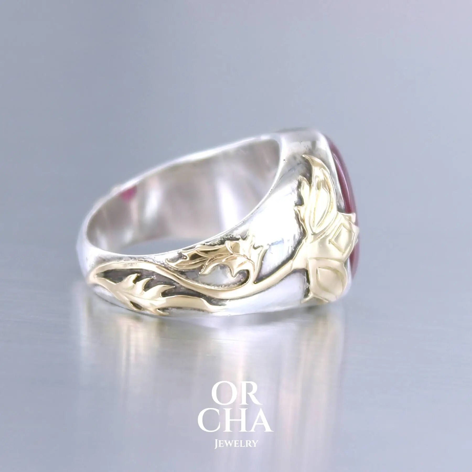 Bague chevalière pour femme en argent massif et or 18k où s'illustrent de chaque cotés de la bague des chardons. Cette bague est sertie d'un cabochon de rubis trapiche de couleur rouge rose. Pierre  translucide traitée au verre au plomb. Taille 60. Bijoux unique, éthique et durable présenté dans un coffret de notre marque, prêt à offrir. Livraison offerte, certificat d'authenticité, service client.