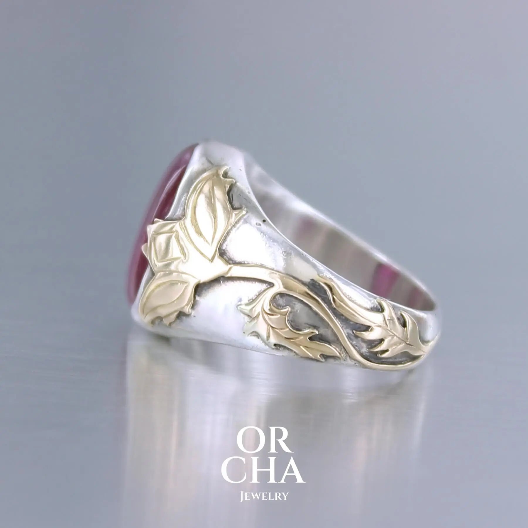 Bague chevalière pour femme en argent massif et or 18k où s'illustrent de chaque cotés de la bague des chardons. Cette bague est sertie d'un cabochon de rubis trapiche de couleur rouge rose. Pierre  translucide traitée au verre au plomb. Taille 60. Bijoux unique, éthique et durable présenté dans un coffret de notre marque, prêt à offrir. Livraison offerte, certificat d'authenticité, service client.