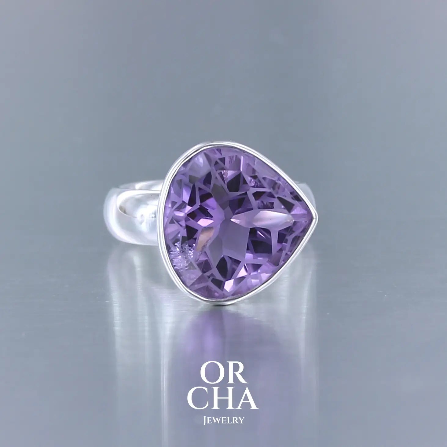 Bague cocktail pour femme en argent massif sertie d'une Améthyste. Pierre facettée en forme de goutte de qualité transparente, propre à l'oeil. Pierre naturelle de couleur violette clair gravée de motifs géométriques de fleur de vie. Tailles 60. Bijoux unique, éthique et durable présenté dans un coffret de notre marque, prêt à offrir. Livraison offerte, certificat d'authenticité, service client.