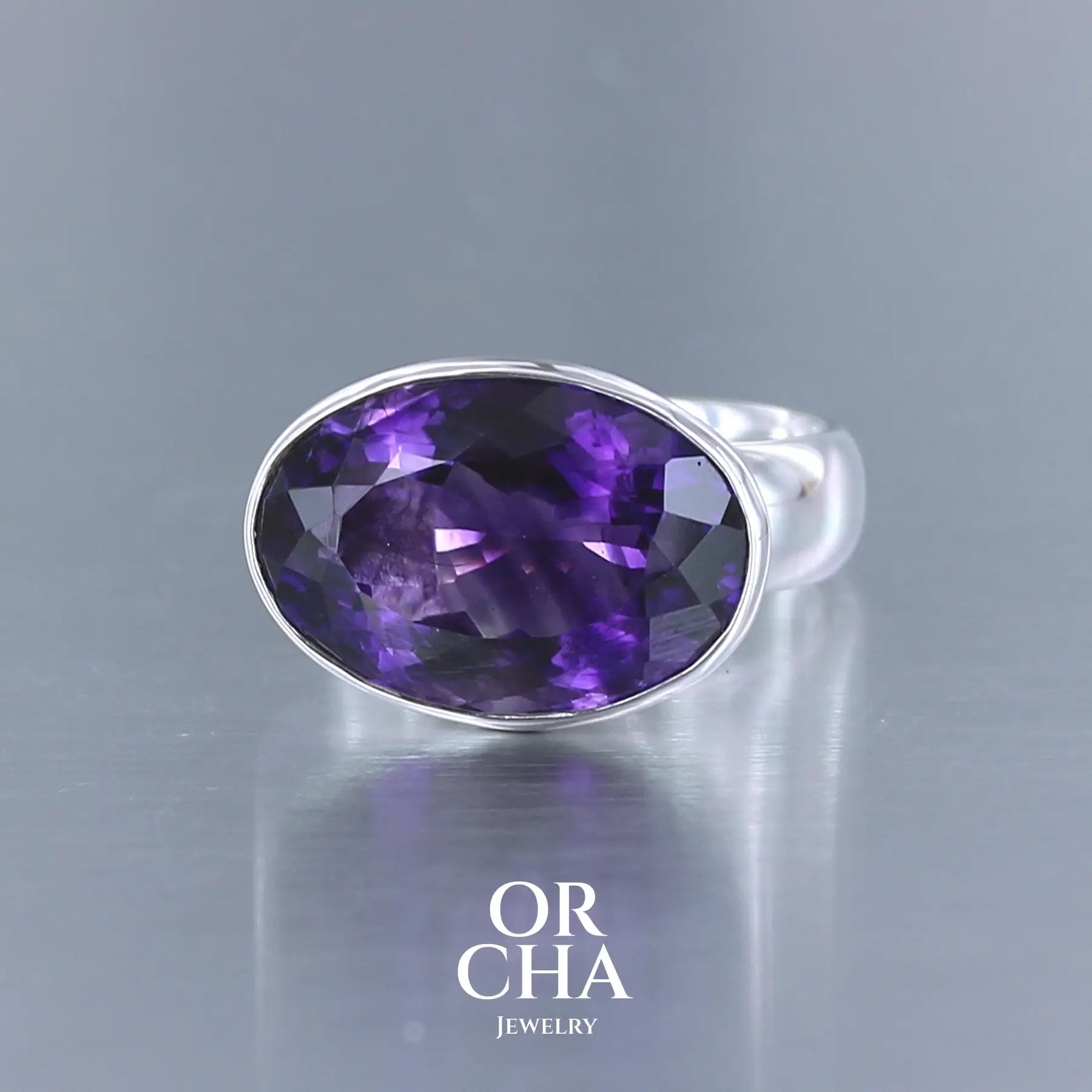 Bague cocktail pour femme en argent massif sertie d'une Améthyste. Pierre facettée de forme ovale de qualité transparente, propre à l'oeil. Pierre naturelle de couleur violette foncée aux légers reflets bleutés. Tailles 61. Bijoux unique, éthique et durable présenté dans un coffret de notre marque, prêt à offrir. Livraison offerte, certificat d'authenticité, service client.