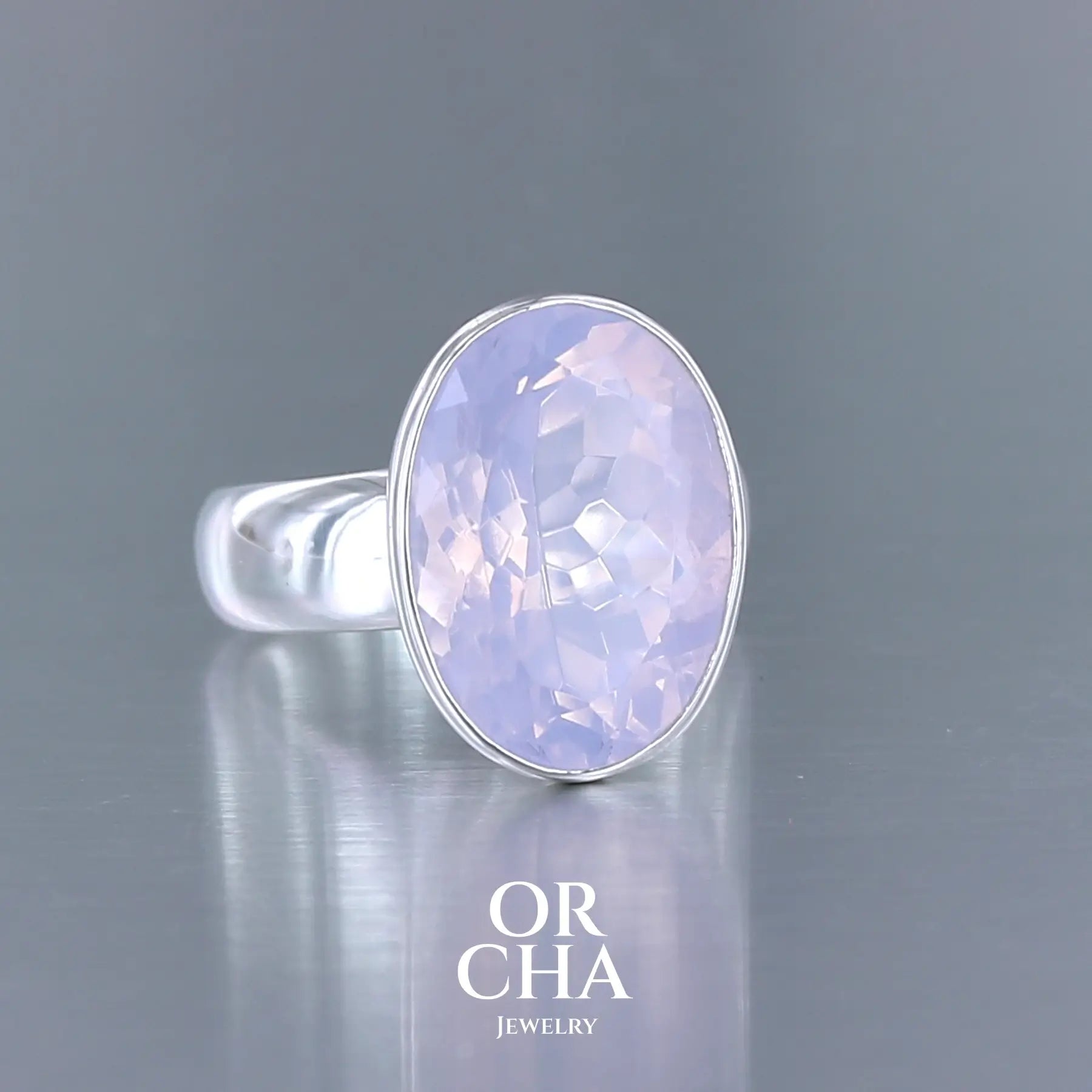 Bague cocktail pour femme en argent massif sertie d'un Quartz lavande. Pierre facettée de forme carrée de qualité transparente, propre à l'oeil. Pierre naturelle de couleur violette pastel teintée de rose avec de légers reflets opalescents. Bague réalisée en taille 60. Bijoux unique, éthique et durable présenté dans un coffret de notre marque, prêt à offrir. Livraison offerte, certificat d'authenticité, service client.