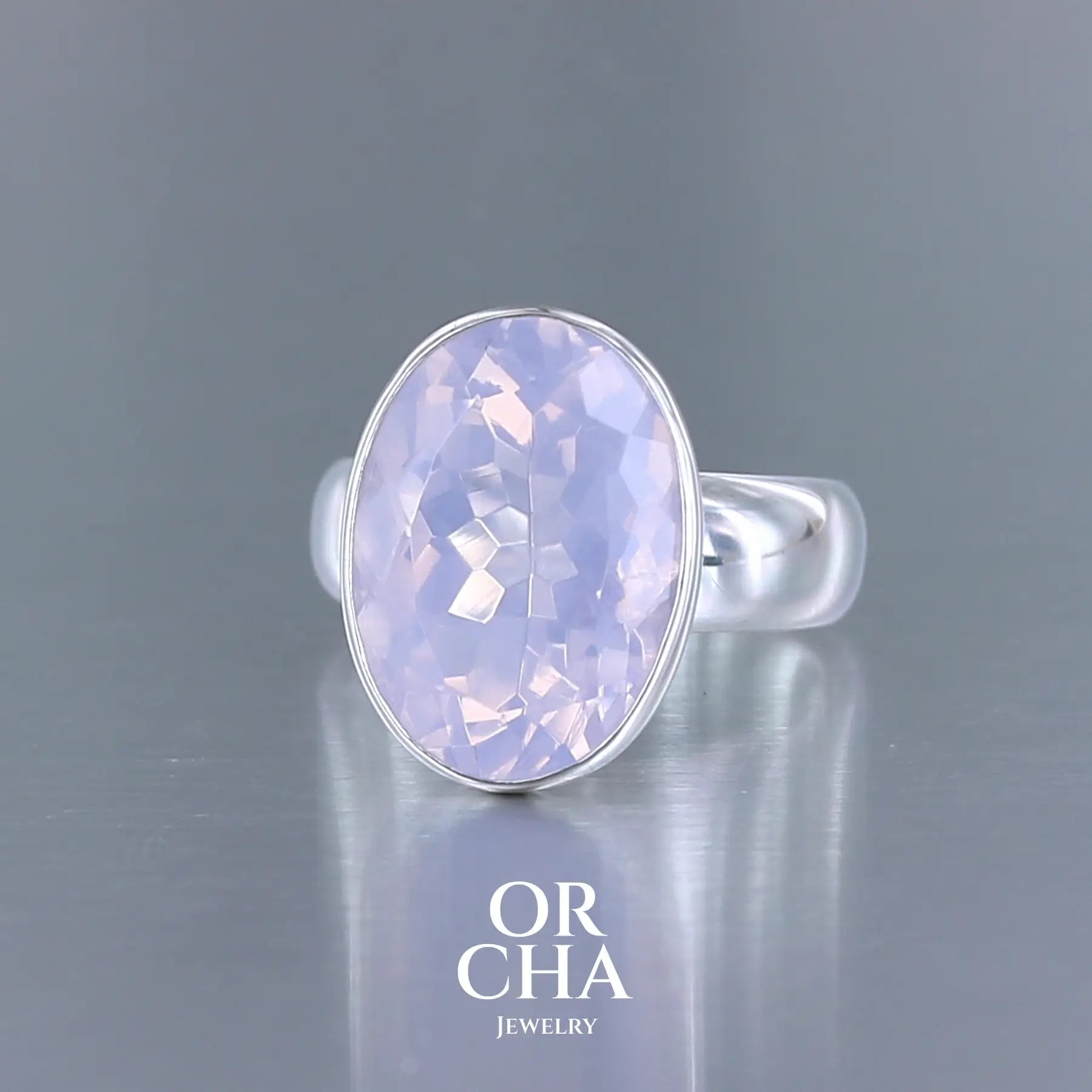 Bague cocktail pour femme en argent massif sertie d'un Quartz lavande. Pierre facettée de forme carrée de qualité transparente, propre à l'oeil. Pierre naturelle de couleur violette pastel teintée de rose avec de légers reflets opalescents. Bague réalisée en taille 60. Bijoux unique, éthique et durable présenté dans un coffret de notre marque, prêt à offrir. Livraison offerte, certificat d'authenticité, service client.