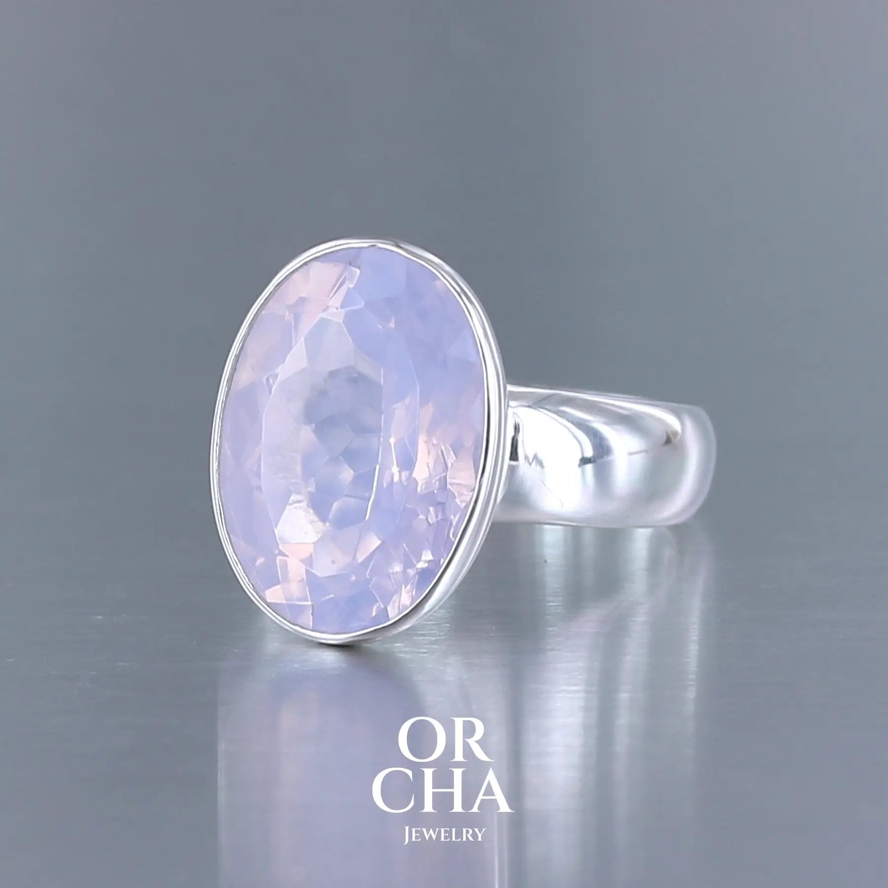 Bague cocktail pour femme en argent massif sertie d'un Quartz lavande. Pierre facettée de forme carrée de qualité transparente, propre à l'oeil. Pierre naturelle de couleur violette pastel teintée de rose avec de légers reflets opalescents. Bague réalisée en taille 60. Bijoux unique, éthique et durable présenté dans un coffret de notre marque, prêt à offrir. Livraison offerte, certificat d'authenticité, service client.