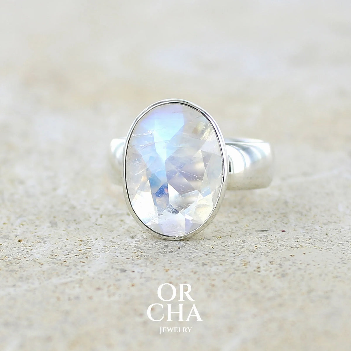 Bague cocktail pour femme en argent massif 925 sertie d'une Labradorite blanche taillée de 6,7 carats incolore aux reflets bleutés et arc en ciel. Pierre transparente avec inclusions. Bijoux unique réalisée en taille 57 par Orchajewelry