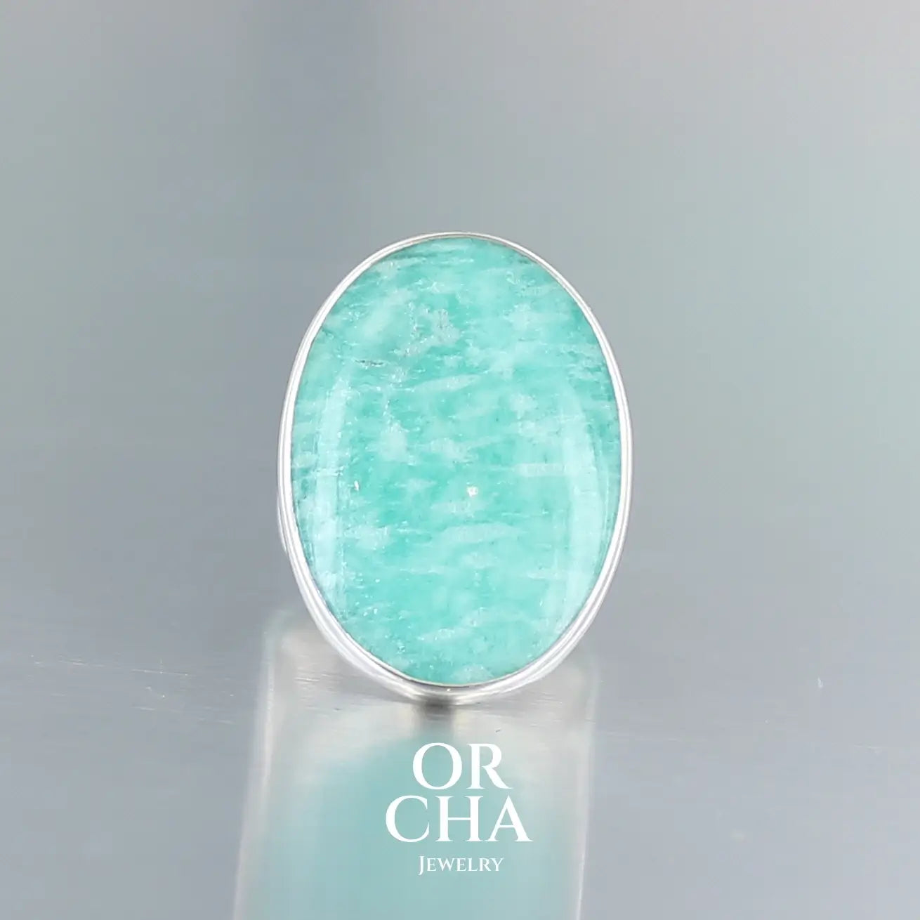 Bague pour femme en argent massif sertie d'une Amazonite. Pierre cabochon de forma ovale, pierre naturelle de couleur bleu vert présentant de légère marbrures blanches. Qualité translucide. Taille 52. Bijoux unique, éthique et durable présenté dans un coffret de notre marque, prêt à offrir. Livraison offerte, certificat d'authenticité, service client