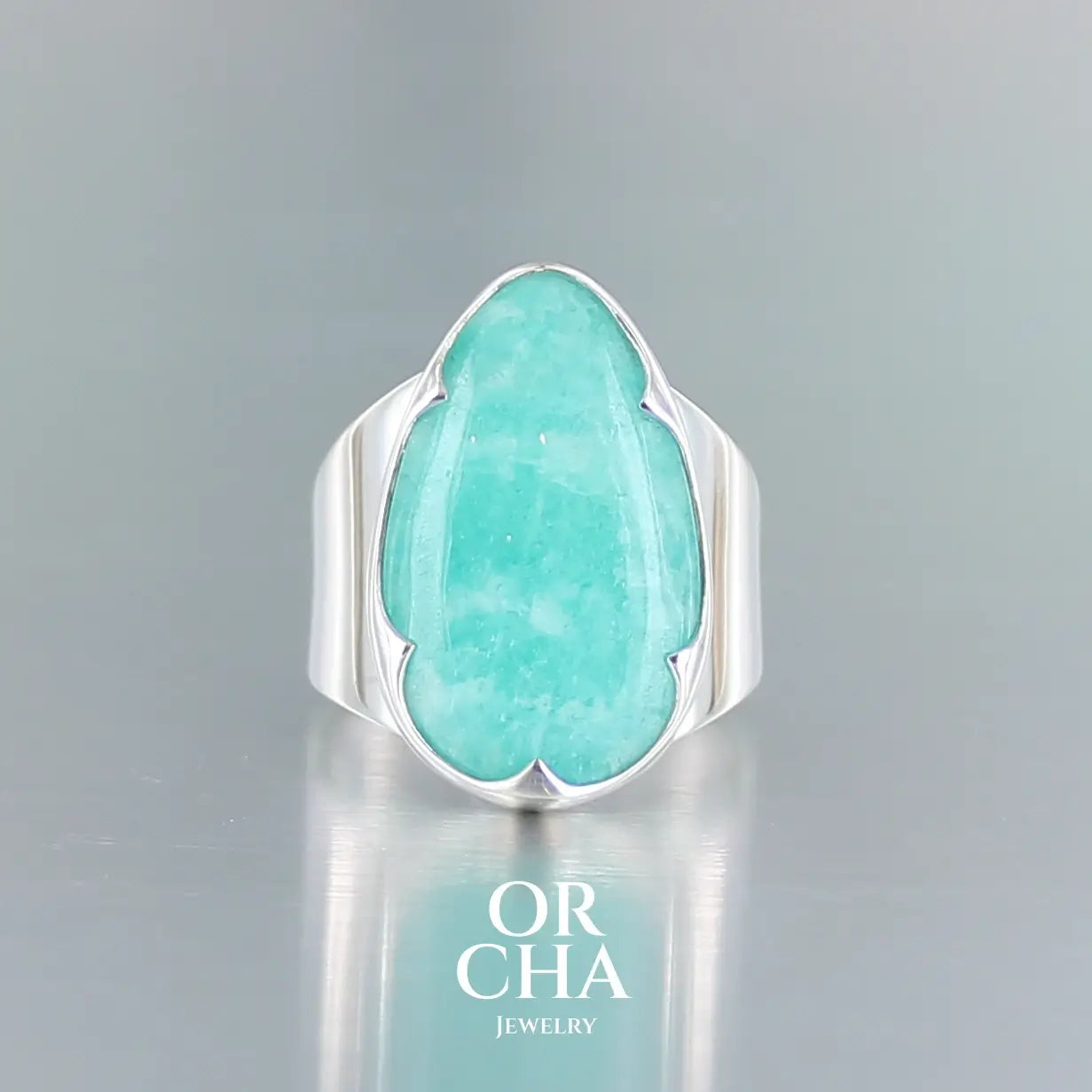 Bague pour femme a large bande en argent massif sertie d'une Amazonite. Pierre cabochon en forme de goutte, pierre naturelle de couleur bleu vert présentant de légère marbrures blanches. Qualité translucide. Taille 58. Bijoux unique, éthique et durable présenté dans un coffret de notre marque, prêt à offrir. Livraison offerte, certificat d'authenticité, service client.
