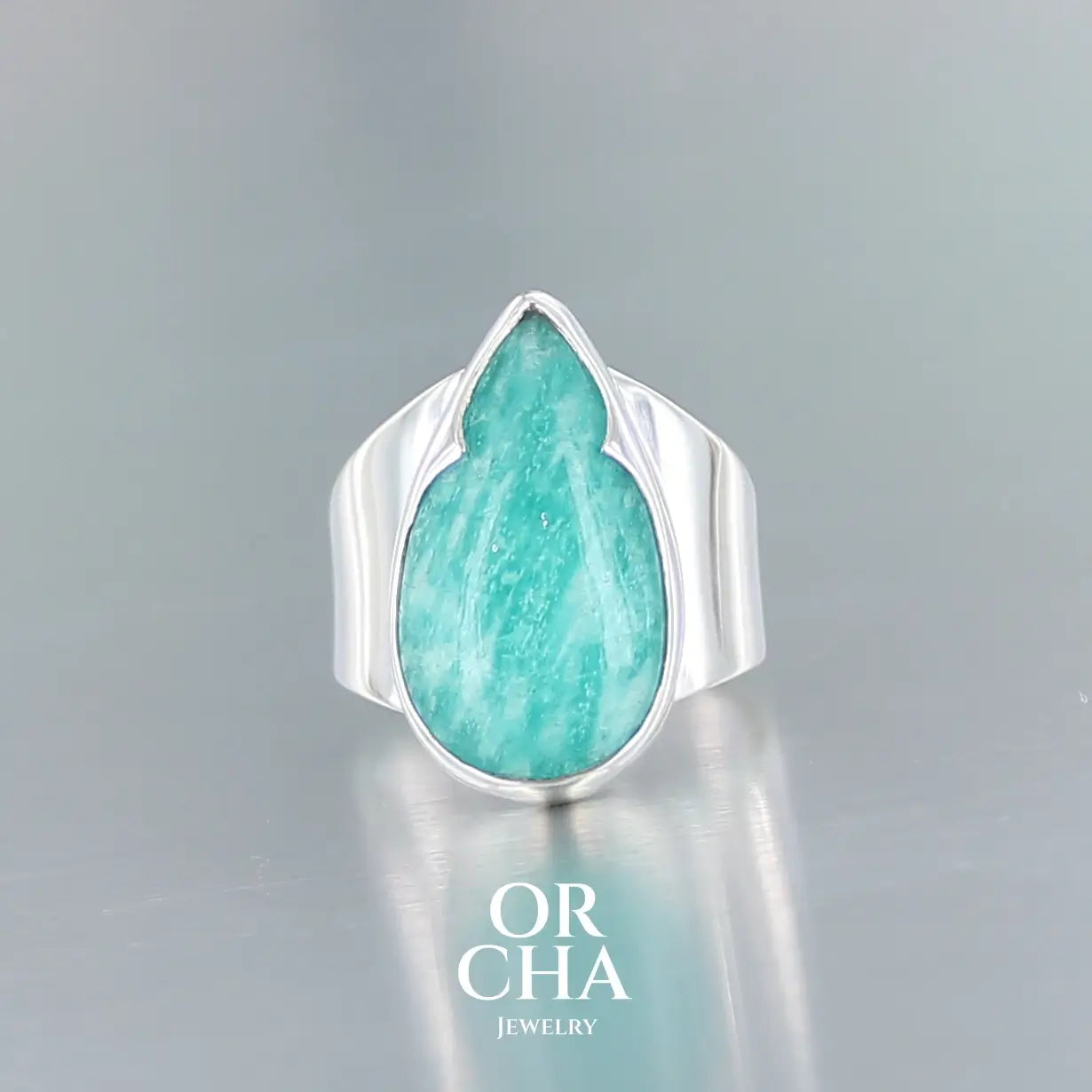 Bague pour femme en argent massif sertie d'une Amazonite. Pierre cabochon en forme de goutte, pierre naturelle de couleur bleu vert présentant de légère marbrures blanches. Qualité translucide. Taille 52. Bijoux unique, éthique et durable présenté dans un coffret de notre marque, prêt à offrir. Livraison offerte, certificat d'authenticité, service client.