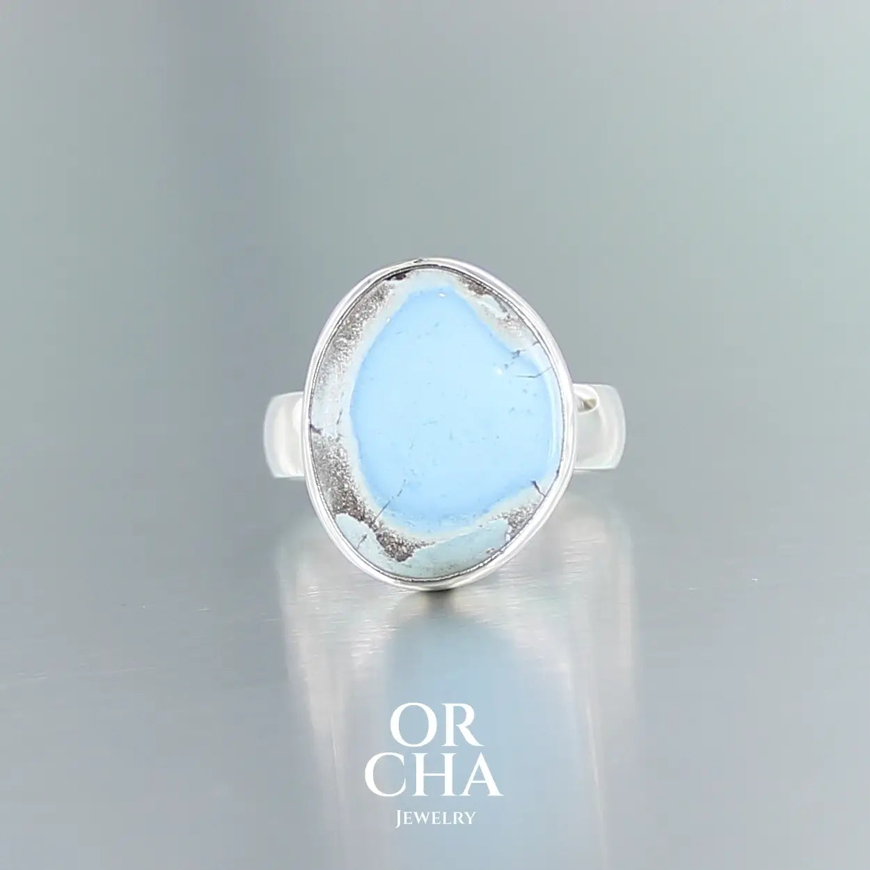Bague de créateur en argent massif pour femme sertie d'une Turquoise golden hill. Pierre cabochon de forme libre de qualité opaque. Pierre naturelle de couleur bleu ciel, gris et brun. Bague réalisée en taille 54. Bijoux unique, éthique et durable présenté dans un coffret de notre marque, prêt à offrir. Livraison offerte, certificat d'authenticité, service client.