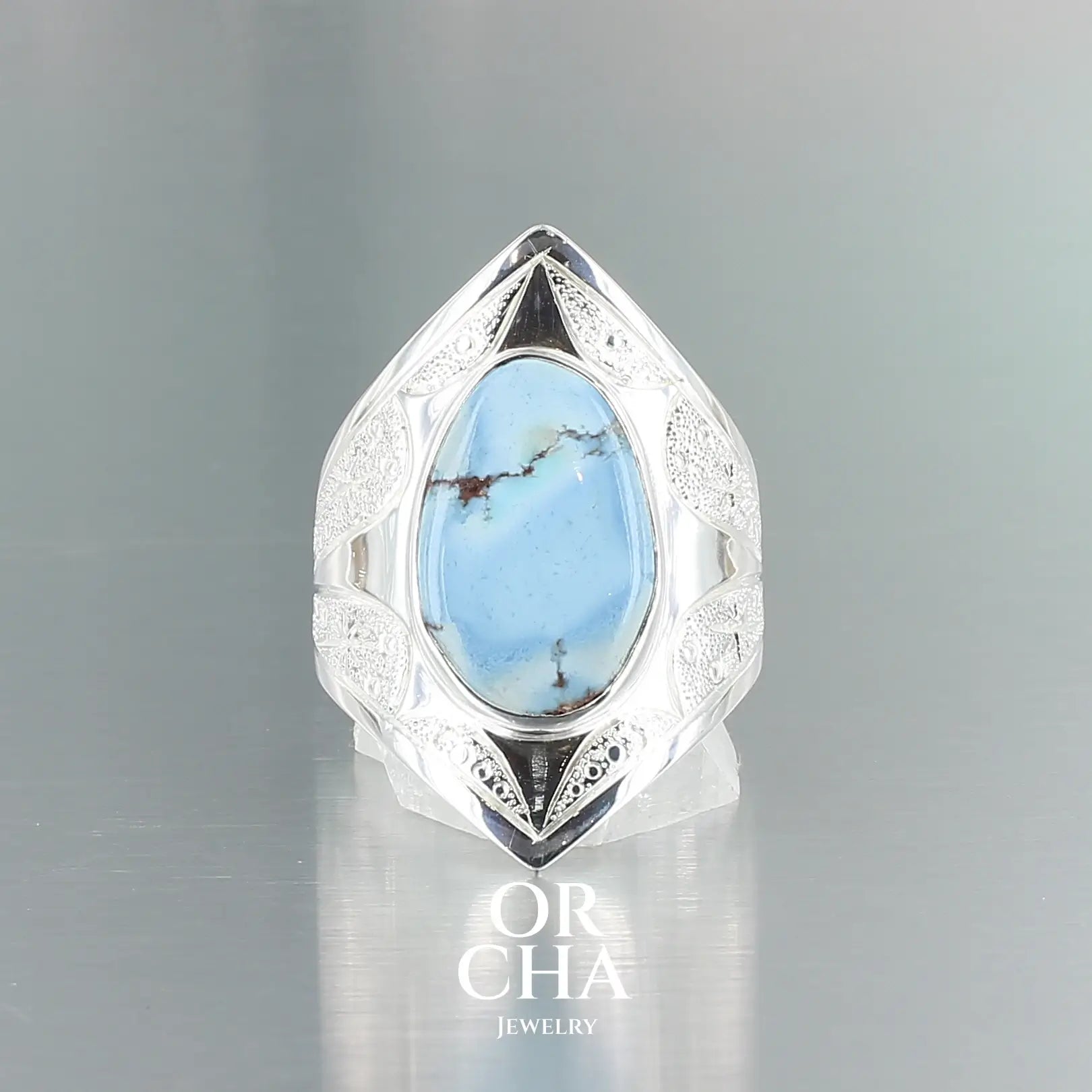 Bague pour femme en argent massif sculptées d'étoiles et autres corps célestes sertie d'une Turquoise Golden Hill. Pierre cabochon en forme de goutte, pierre naturelle aux nuances de bleus . Qualité opaque, pierre non stabilisée. Taille 54. Bijoux unique, éthique et durable présenté dans un coffret de notre marque, prêt à offrir. Livraison offerte, certificat d'authenticité, service client.