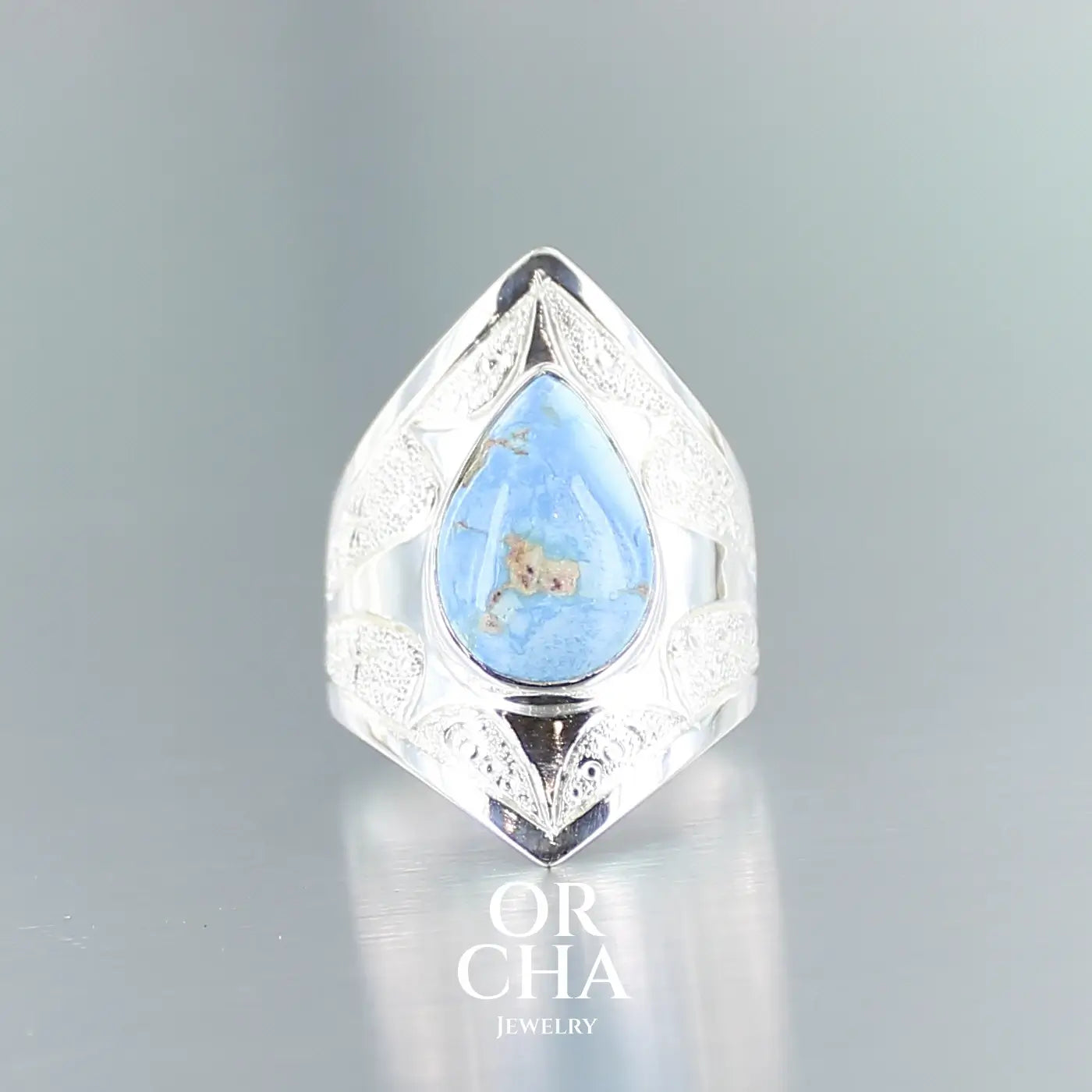 Bague pour femme en argent massif sculptées d'étoiles et autres corps célestes sertie d'une Turquoise Golden Hill. Pierre cabochon en forme de goutte, pierre naturelle aux nuances de bleus . Qualité opaque, pierre non stabilisée. Taille 52. Bijoux unique, éthique et durable présenté dans un coffret de notre marque, prêt à offrir. Livraison offerte, certificat d'authenticité, service client.