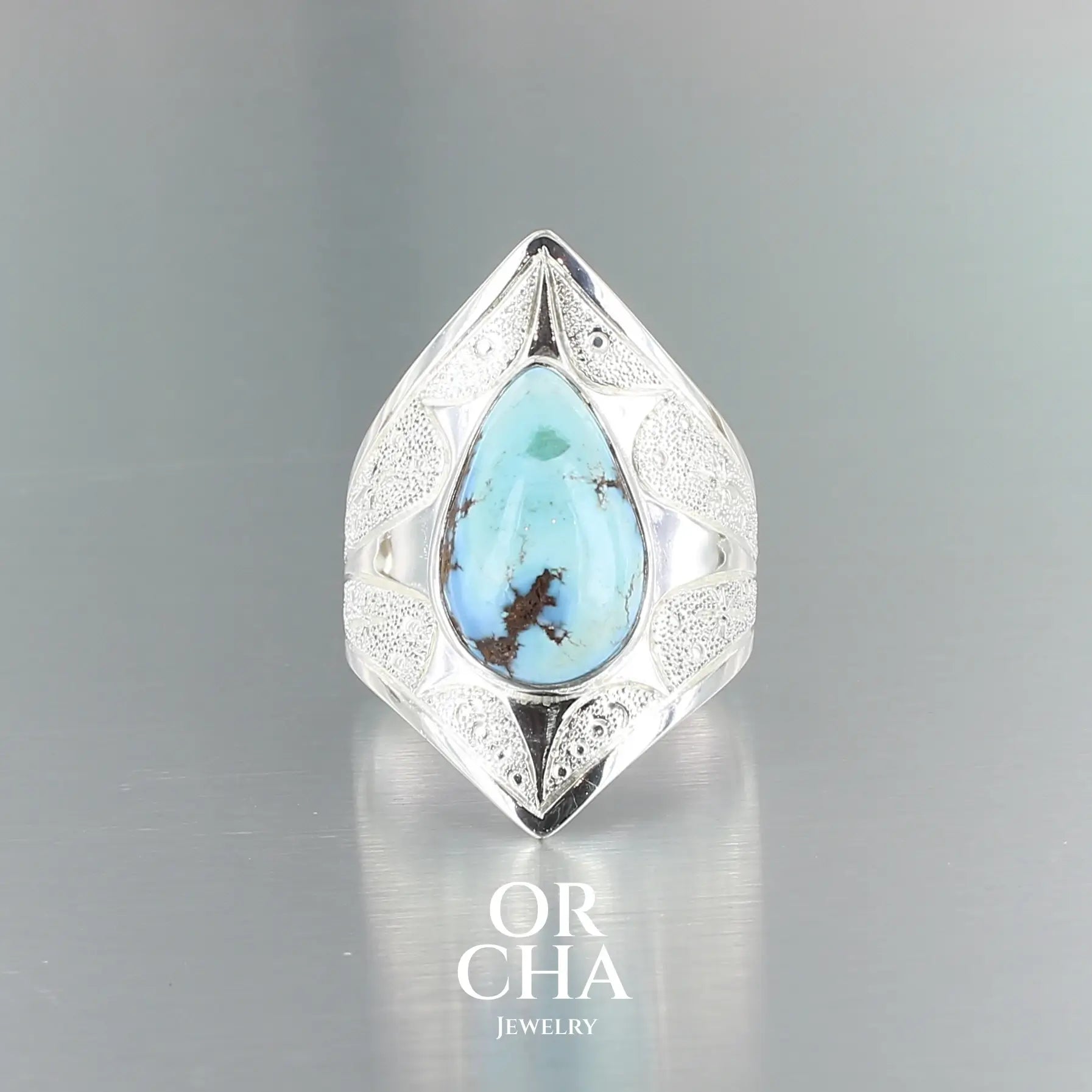Bague pour femme en argent massif sculptées d'étoiles et autres corps célestes sertie d'une Turquoise Golden Hill. Pierre cabochon en forme de goutte, pierre naturelle aux nuances de bleus . Qualité opaque, pierre non stabilisée. Taille 59. Bijoux unique, éthique et durable présenté dans un coffret de notre marque, prêt à offrir. Livraison offerte, certificat d'authenticité, service client.