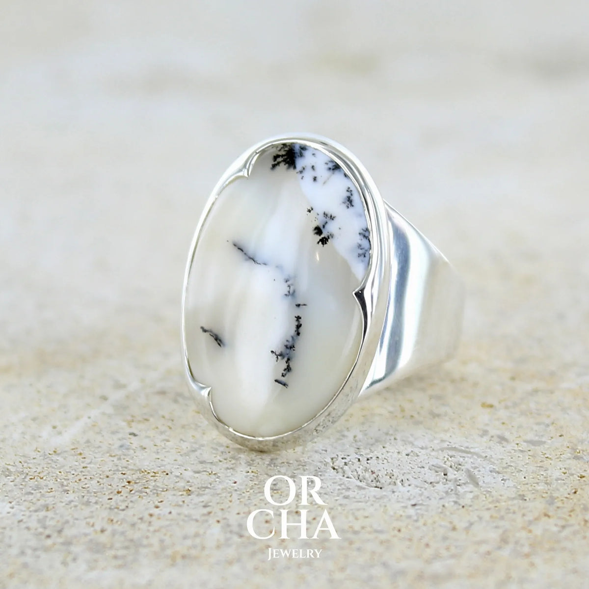 Bague pour femme en argent massif sertie d'un cabochon ovale d'agate dendritique de couleur blanc pur et noir. Pierre opaque translucide à inclusions paysages de dendrites de manganèse noires contrastées. Bijou unique réalisé en taille 54 par Orchajewelry