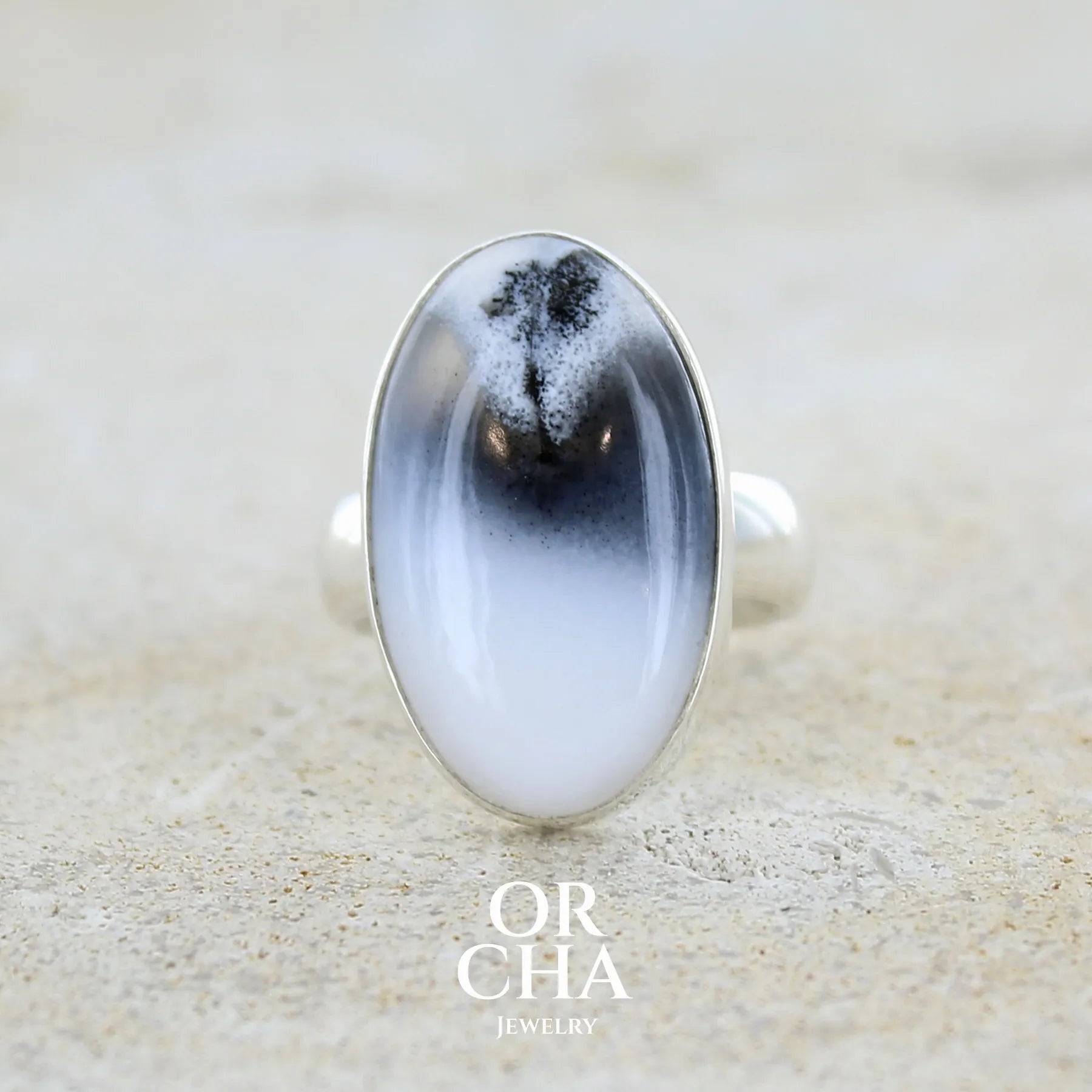 Bague pour femme en argent massif sertie d'un cabochon ovale d'agate dendritique de couleur blanc pur et noir. Pierre opaque translucide à inclusions paysages de dendrites de manganèse noires contrastées. Bijou unique réalisée en taille 54 par Orchajewelry