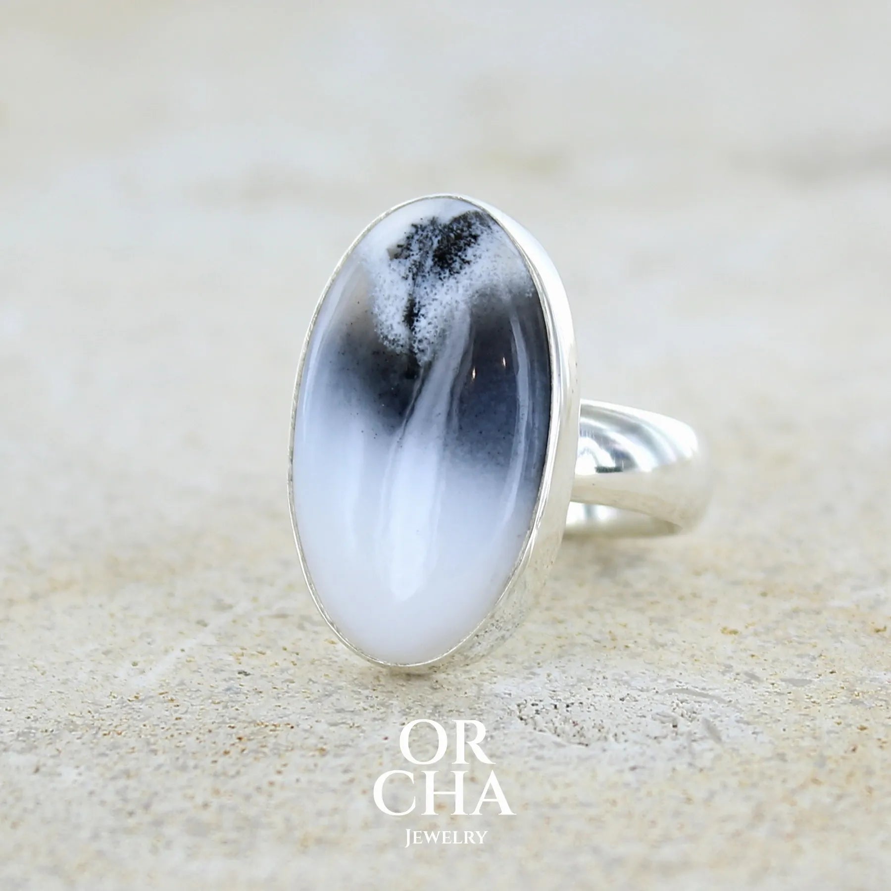 Bague pour femme en argent massif sertie d'un cabochon ovale d'agate dendritique de couleur blanc pur et noir. Pierre opaque translucide à inclusions paysages de dendrites de manganèse noires contrastées. Bijou unique réalisée en taille 54 par Orchajewelry
