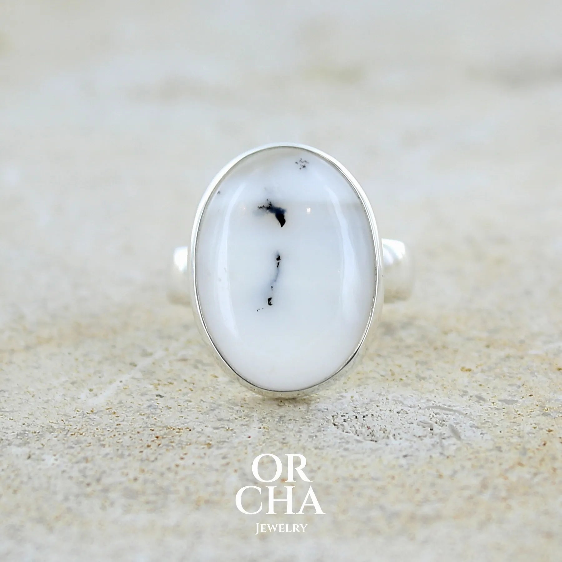 Bague pour femme en argent massif sertie d'un cabochon ovale d'agate dendritique de couleur blanc pur et noir. Pierre opaque à inclusions paysages de dendrites de manganèse noires contrastées. Bijou unique réalisée en taille 54 par Orchajewelry