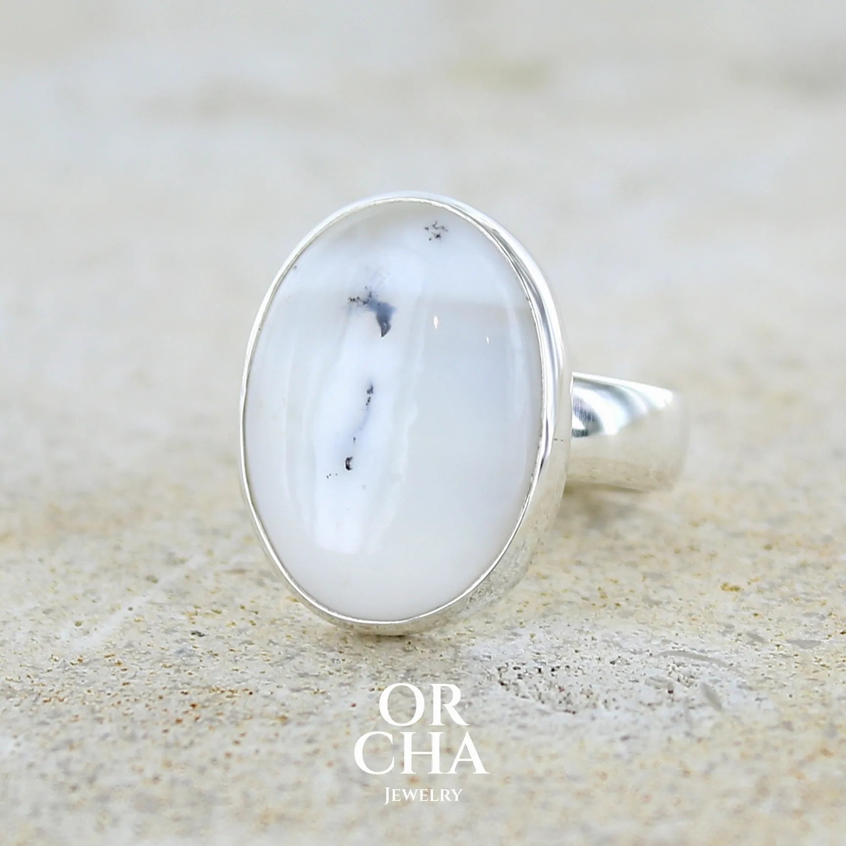 Bague pour femme en argent massif sertie d'un cabochon ovale d'agate dendritique de couleur blanc pur et noir. Pierre opaque à inclusions paysages de dendrites de manganèse noires contrastées. Bijou unique réalisée en taille 54 par Orchajewelry