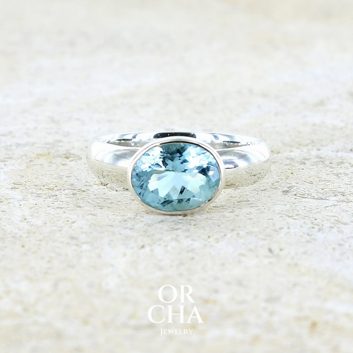 Bague pour femme en argent massif sertie d'une algue-marine de couleur bleu ciel lumineux et intense. Pierre naturelle de qualité transparente propre à l'oeil taillée de forme ovale. Bague unique réalisée en taille 52 par Orcha jewelry