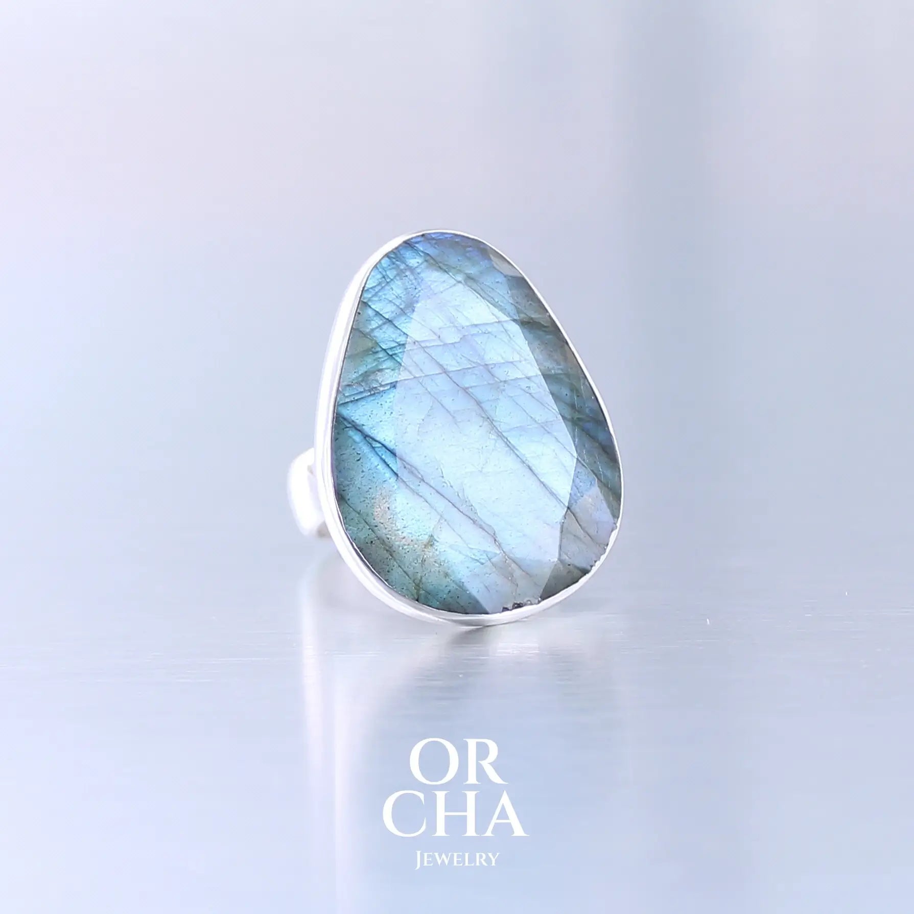 Bague pour femme en argent massif sertie d'une labradorite aux reflets bleus selon la lumière. Pierre facettée naturelle translucide présentant des inclusions fréquents sur ce type de pierre. Taille 58. Bijoux unique, éthique et durable présenté dans un coffret de notre marque, prêt à offrir. Livraison offerte, certificat d'authenticité, service client.
