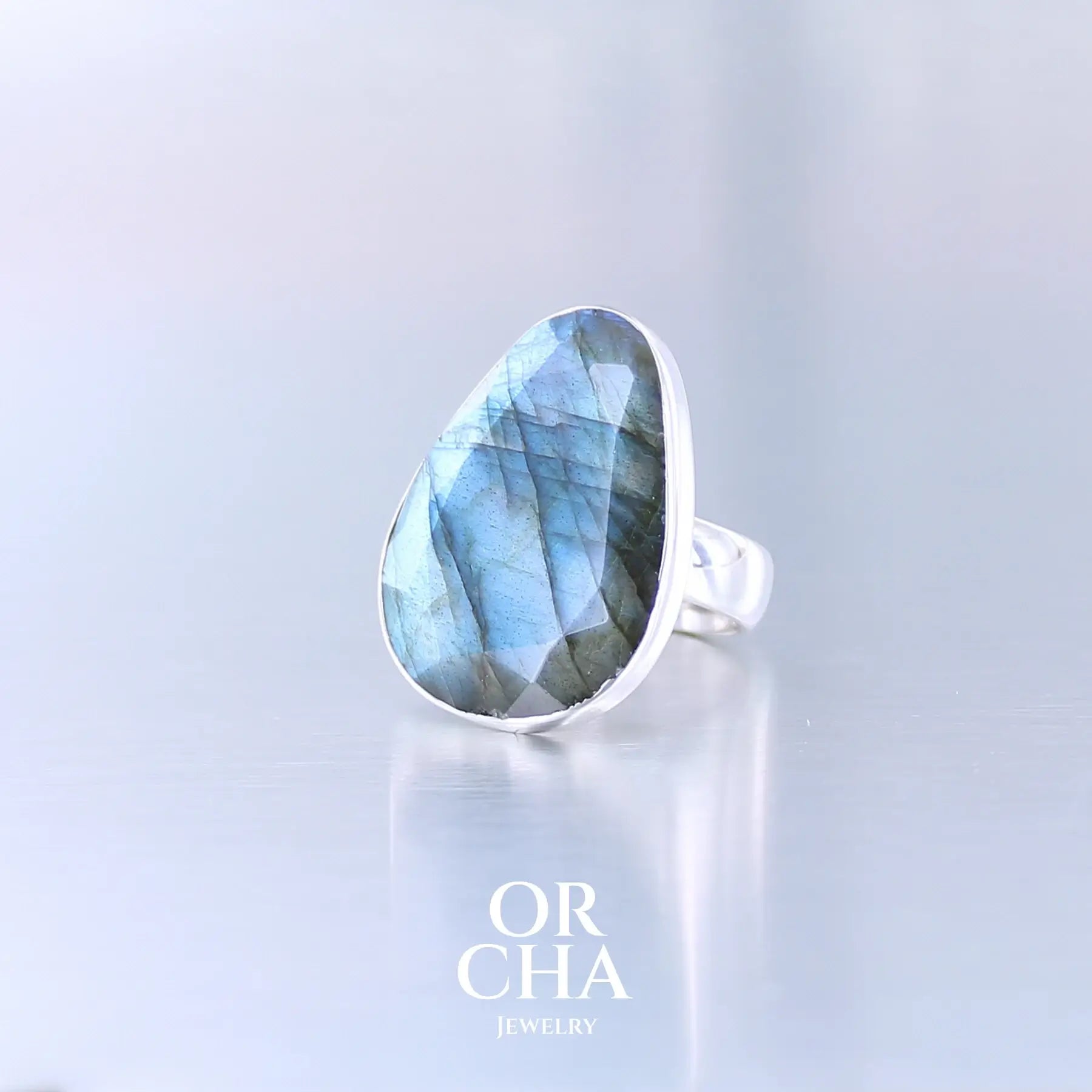 Bague pour femme en argent massif sertie d'une labradorite aux reflets bleus selon la lumière. Pierre facettée naturelle translucide présentant des inclusions fréquents sur ce type de pierre. Taille 58. Bijoux unique, éthique et durable présenté dans un coffret de notre marque, prêt à offrir. Livraison offerte, certificat d'authenticité, service client.