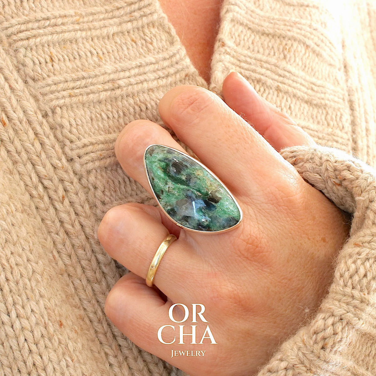 Bague pour femme en argent massif sertie d'un cabochon de pierre verte scintillante à inclusions bleues et noires. Pierre de qualité opaque et de forme libre. Bijou unique réalisée en taille 56 par Orchajewelry
