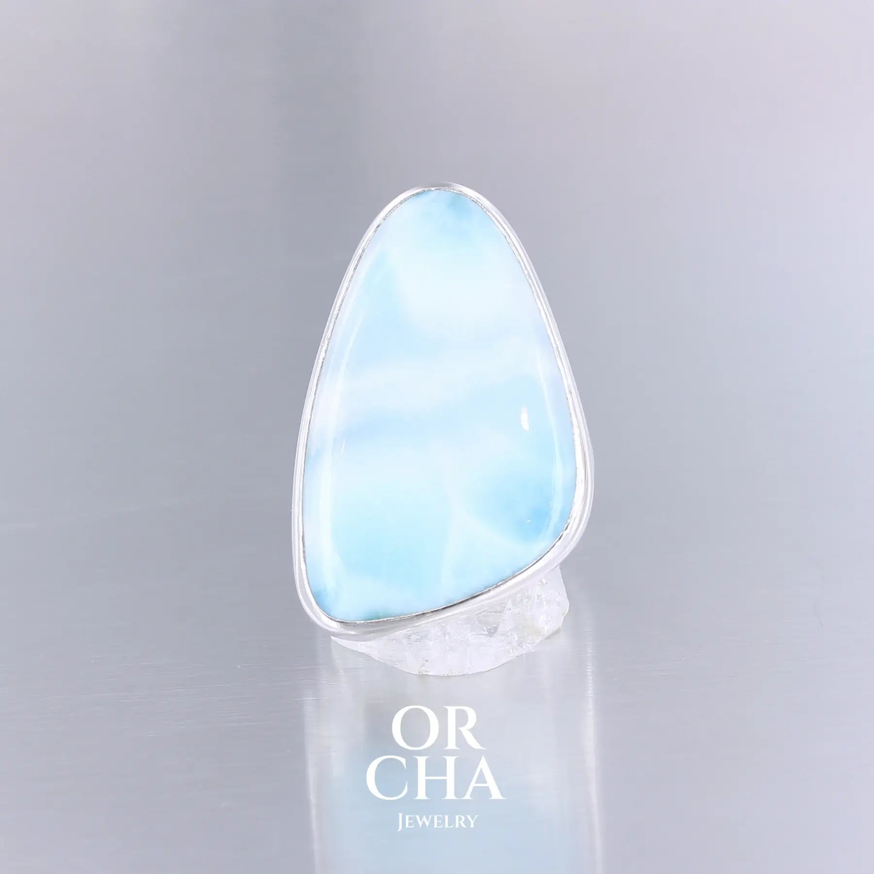 Grande bague pour femme en argent massif sertie d'un Larimar de République dominicaine. Cabochon de forme fantaisie, pierre naturelle de couleur bleu lagon présentant des marbrures blanches. Qualité translucide. Taille 58. Bijoux unique, éthique et durable présenté dans un coffret de notre marque, prêt à offrir. Livraison offerte, certificat d'authenticité, service client.