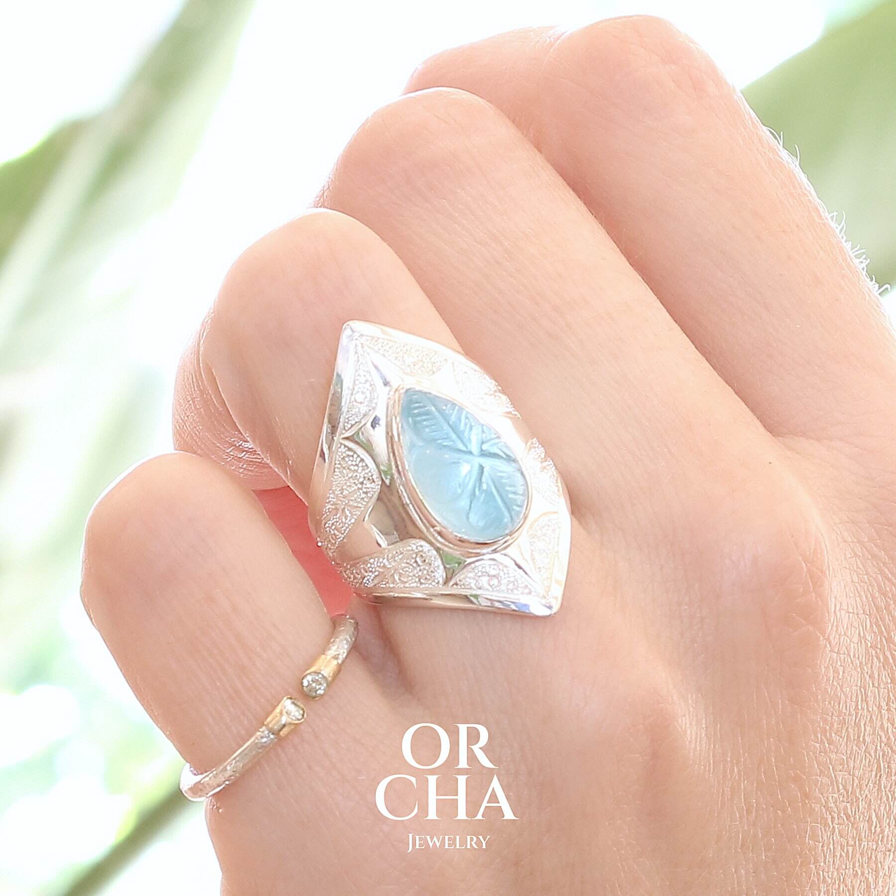 Bague pour femme en argent massif sculptées d'étoiles et autres corps célestes sertie d'une Topaze bleue. Cabochon sculptée en feuille de couleur bleu ciel en forme de goutte. Bague réalisée en taille 54. Bijoux unique, éthique et durable présenté dans un coffret de notre marque, prêt à offrir. Livraison offerte, certificat d'authenticité, service client.