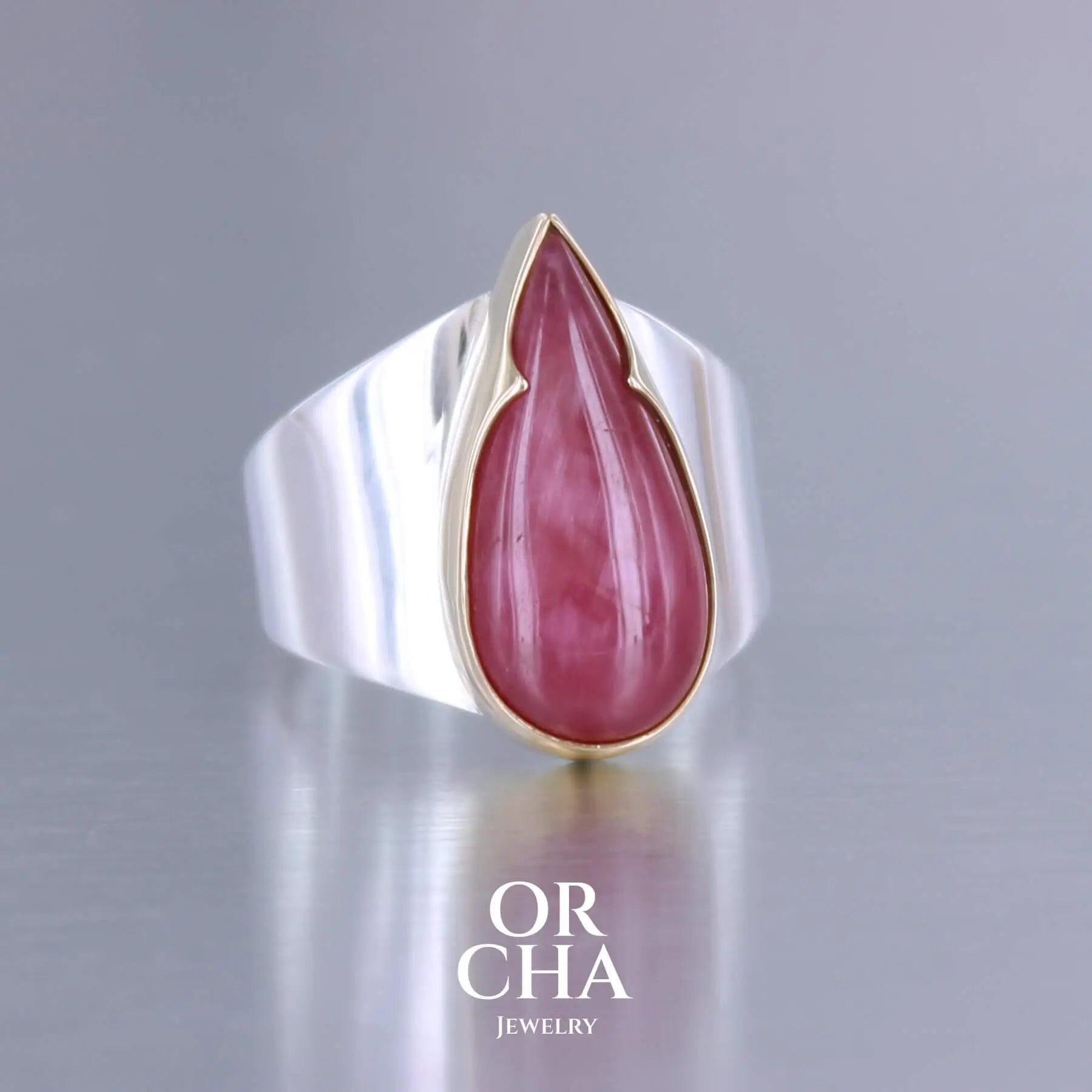 Grande bague pour femme en or 18k et argent massif sertie d'une Rhodonite. Pierre cabochon en forme de goutte, pierre naturelle de qualité rare de couleur rouge coquelicot. Pierre fine de qualité opaque. Taille 56. Bijoux unique, éthique et durable présenté dans un coffret de notre marque, prêt à offrir. Livraison offerte, certificat d'authenticité, service client.
