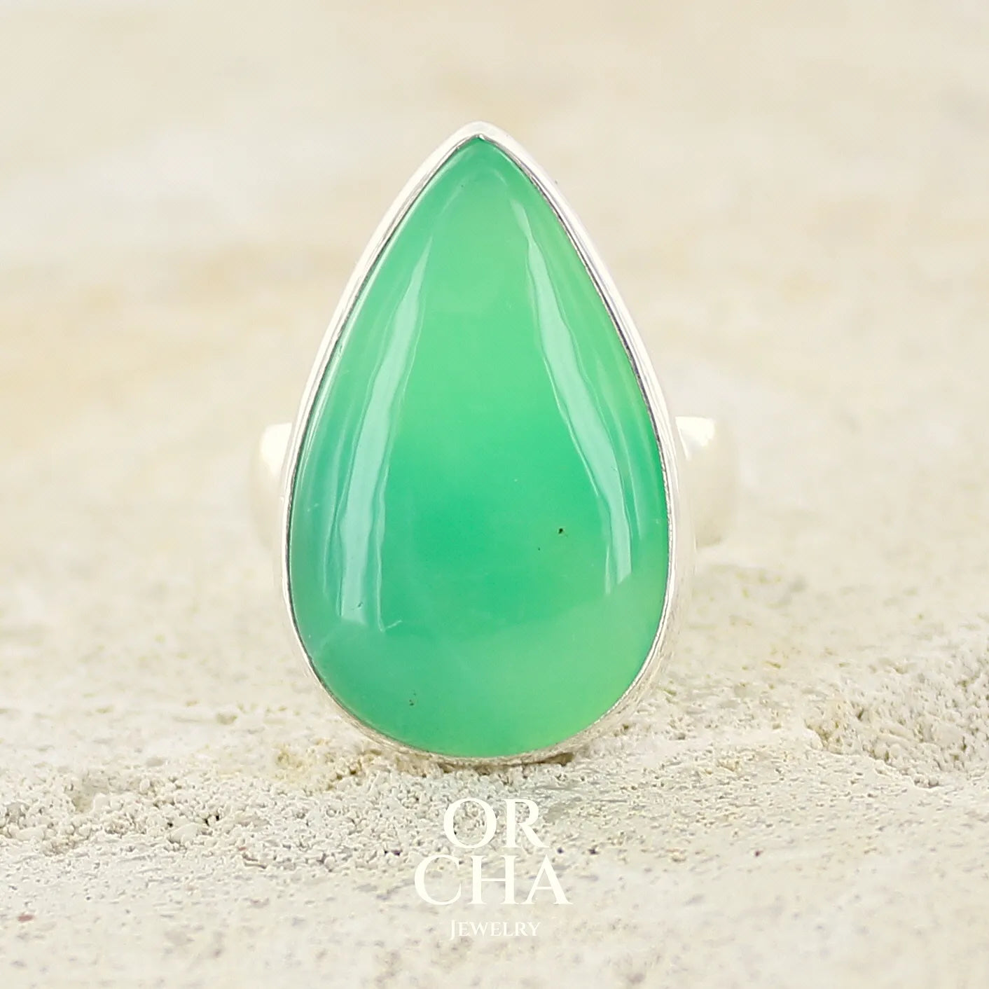 Bague pour femme en argent massif, sertie d'un cabochon de Chrysoprase. Pierre taillée en forme de goutte de qualité opaque. Bijoux unique réalisé en taille 58 par Orcha Jewelry