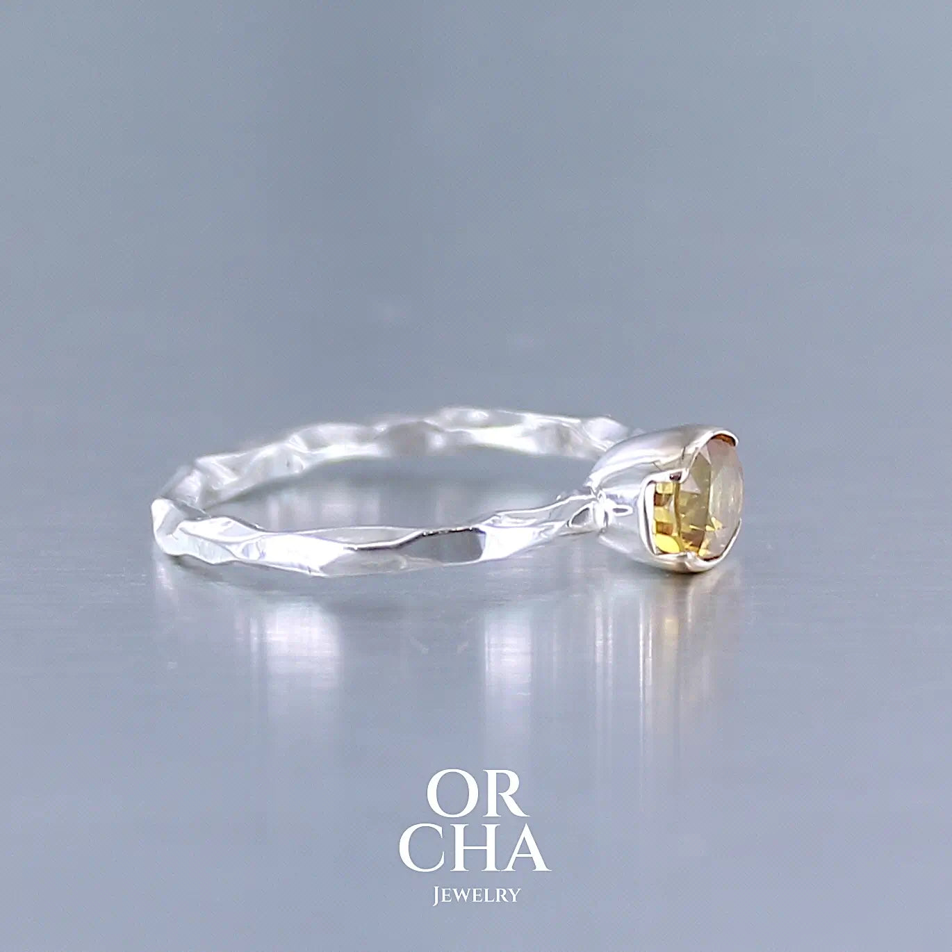 Photo de profil d'une bague anneau pour femme en argent massif et or 12 k sertie d'un Saphir jaune orangé très lumineux. Pierre facettée de forme ovale, de qualité transparente, propre à l'oeil. Pierre chauffée et traitée au beryllium. Bijoux unique, éthique et durable présenté dans un coffret de notre marque, prêt à offrir. Livraison offerte, certificat d'authenticité, service client.