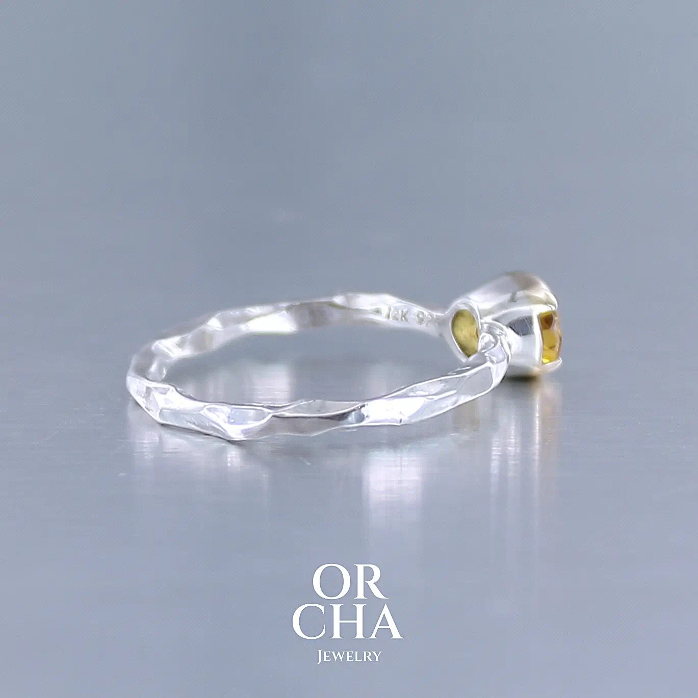 Photo de profil d'une bague anneau pour femme en argent massif et or 12 k sertie d'un Saphir jaune orangé très lumineux. Pierre facettée de forme ovale, de qualité transparente, propre à l'oeil. Pierre chauffée et traitée au beryllium. Bijoux unique, éthique et durable présenté dans un coffret de notre marque, prêt à offrir. Livraison offerte, certificat d'authenticité, service client.