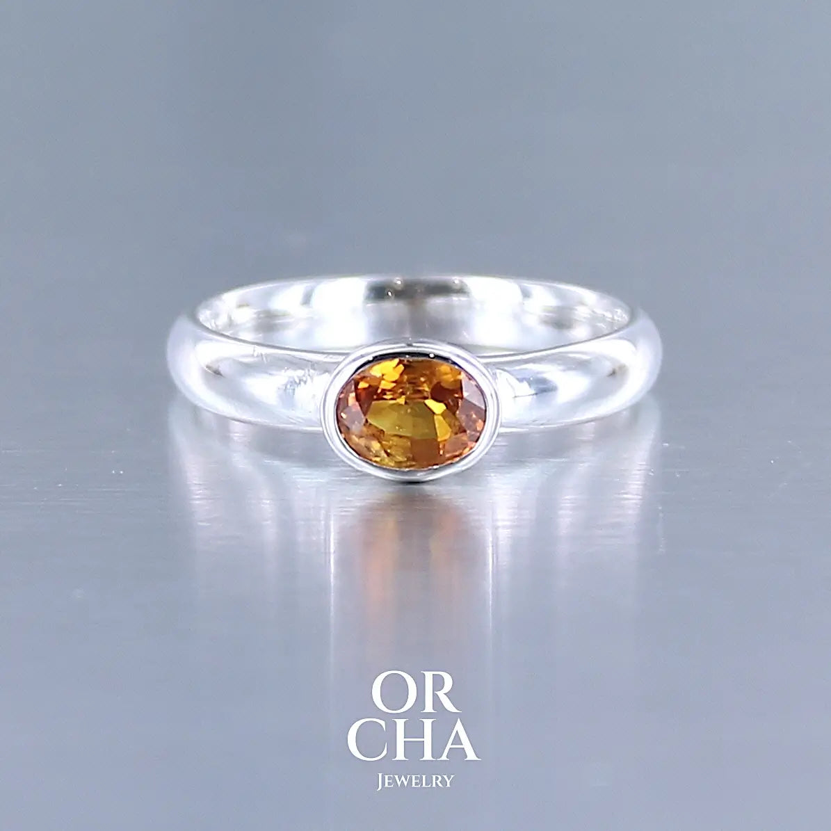 Bague anneau en argent massif sertie d'un Saphir orange. Pierre facettée de forme ovale de qualité transparente, propre à l'oeil. Pierre chauffe et traité au beryllium de couleur orange intense. Tailles 56. Pour homme et femme. Bijoux unique, éthique et durable présenté dans un coffret de notre marque, prêt à offrir. Livraison offerte, certificat d'authenticité, service client.