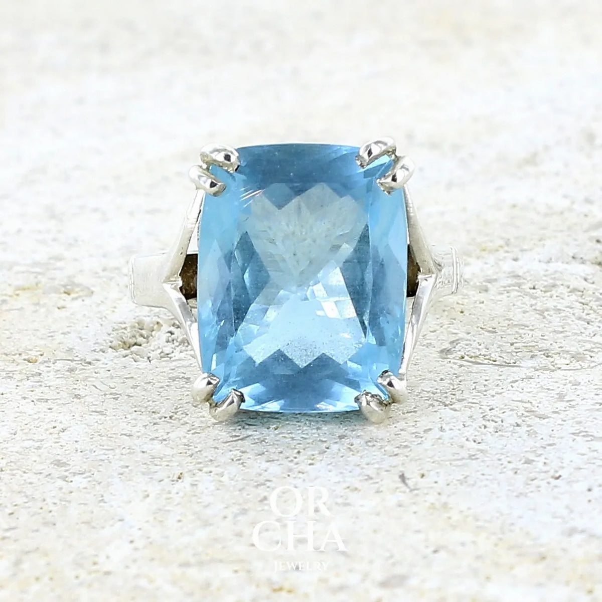 Bague pour femme en argent massif sertie d'une magnifique aigue marine taillée de 10,3 carats de couleur bleue clair intense. Pierre transparente lumineuse comportant de légères inclusions. Bijou unique réalisée en taille 54 par Orchajewelry