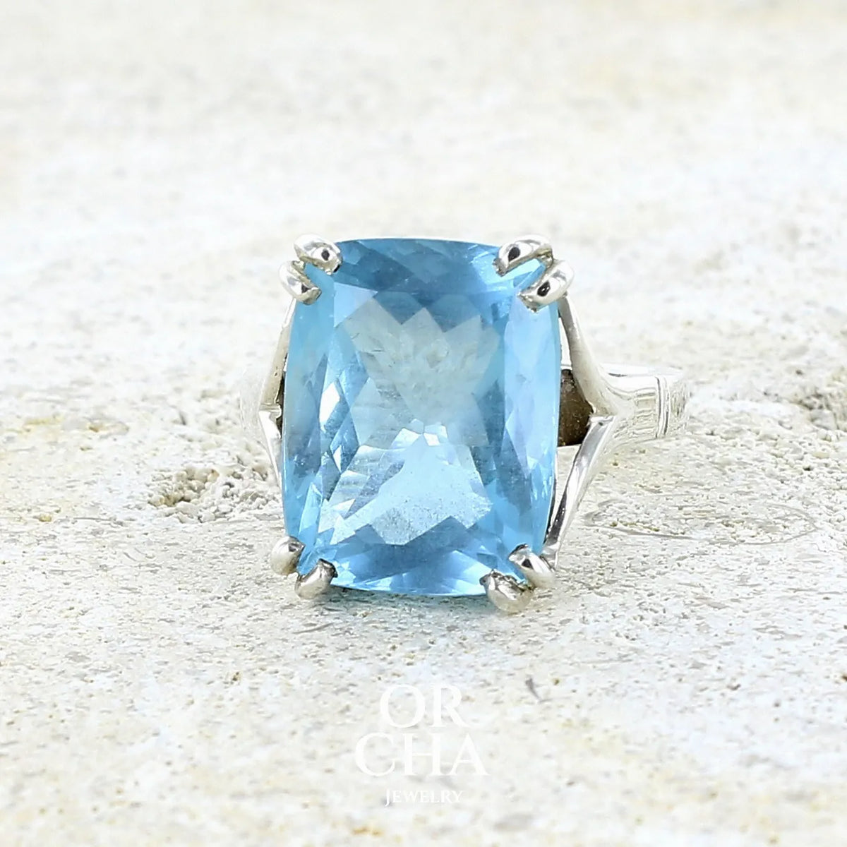 Bague pour femme en argent massif sertie d'une magnifique aigue marine taillée de 10,3 carats de couleur bleue clair intense. Pierre transparente lumineuse comportant de légères inclusions. Bijou unique réalisée en taille 54 par Orchajewelry