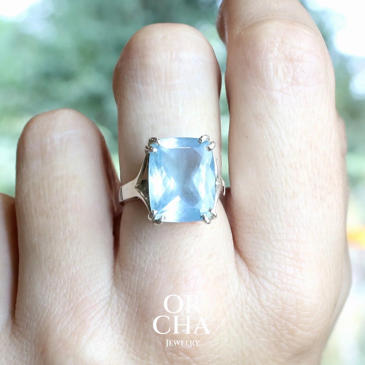 Bague pour femme en argent massif sertie d'une magnifique aigue marine taillée de 10,3 carats de couleur bleue clair intense. Pierre transparente lumineuse comportant de légères inclusions. Bijou unique réalisée en taille 54 par Orchajewelry