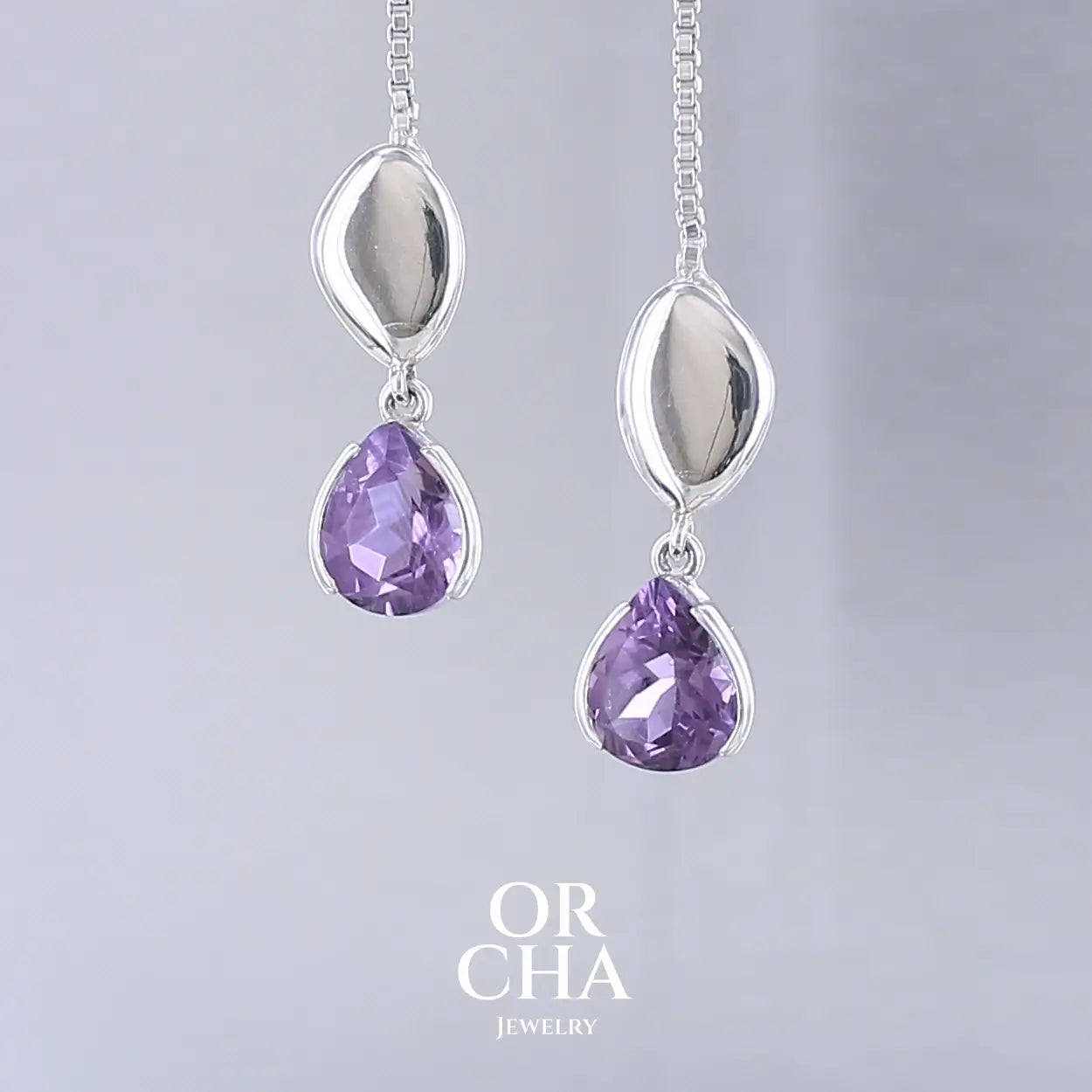 Boucles d'oreilles pendantes pour femme en argent massif serties d'Améthyste. Pierres facettées en forme de goutte de qualités transparentes, propre à l'oeil. Pierres naturelles de couleur violet moyen .Bijoux unique, éthique et durable présenté dans un coffret de notre marque, prêt à offrir. Livraison offerte, certificat d'authenticité, service client.