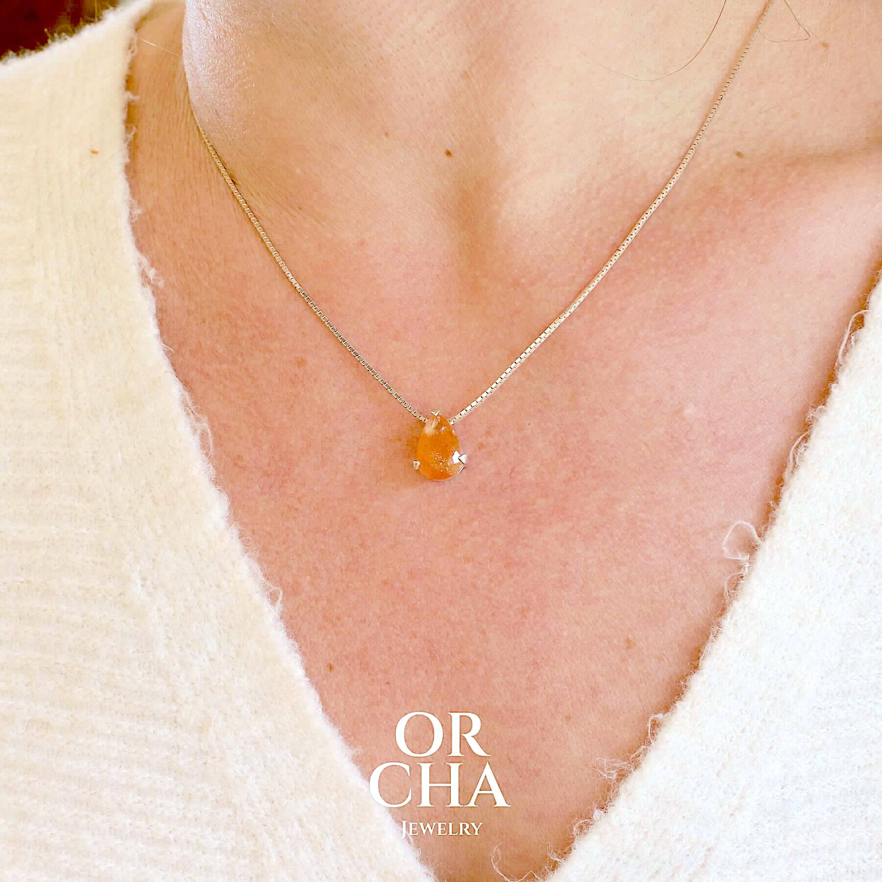 Collier solitaire pour femme en argent massif serti d'une pierre de soleil. Pierre de couleur orange facettée en forme de goutte, qualité transparente à  inclusions scintillantes dorées orangées. Pendentif monté sur une chaine en argent sterling de type maille carrée miroir de 0,94 mm d'épaisseur et de 40 cm de longueur. Bijoux unique, éthique et durable présenté dans un coffret de notre marque, prêt à offrir. Livraison offerte, certificat d'authenticité, service client.