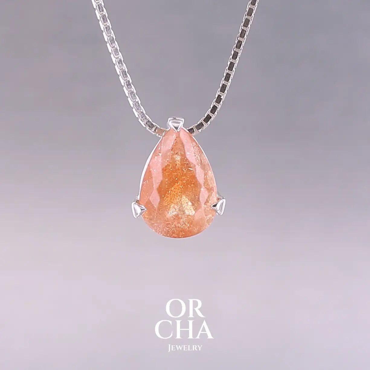 Collier solitaire pour femme en argent massif serti d'une pierre de soleil. Pierre de couleur orange facettée en forme de goutte, qualité transparente à  inclusions scintillantes dorées orangées. Pendentif monté sur une chaine en argent sterling de type maille carrée miroir de 0,94 mm d'épaisseur et de 40 cm de longueur. Bijoux unique, éthique et durable présenté dans un coffret de notre marque, prêt à offrir. Livraison offerte, certificat d'authenticité, service client.