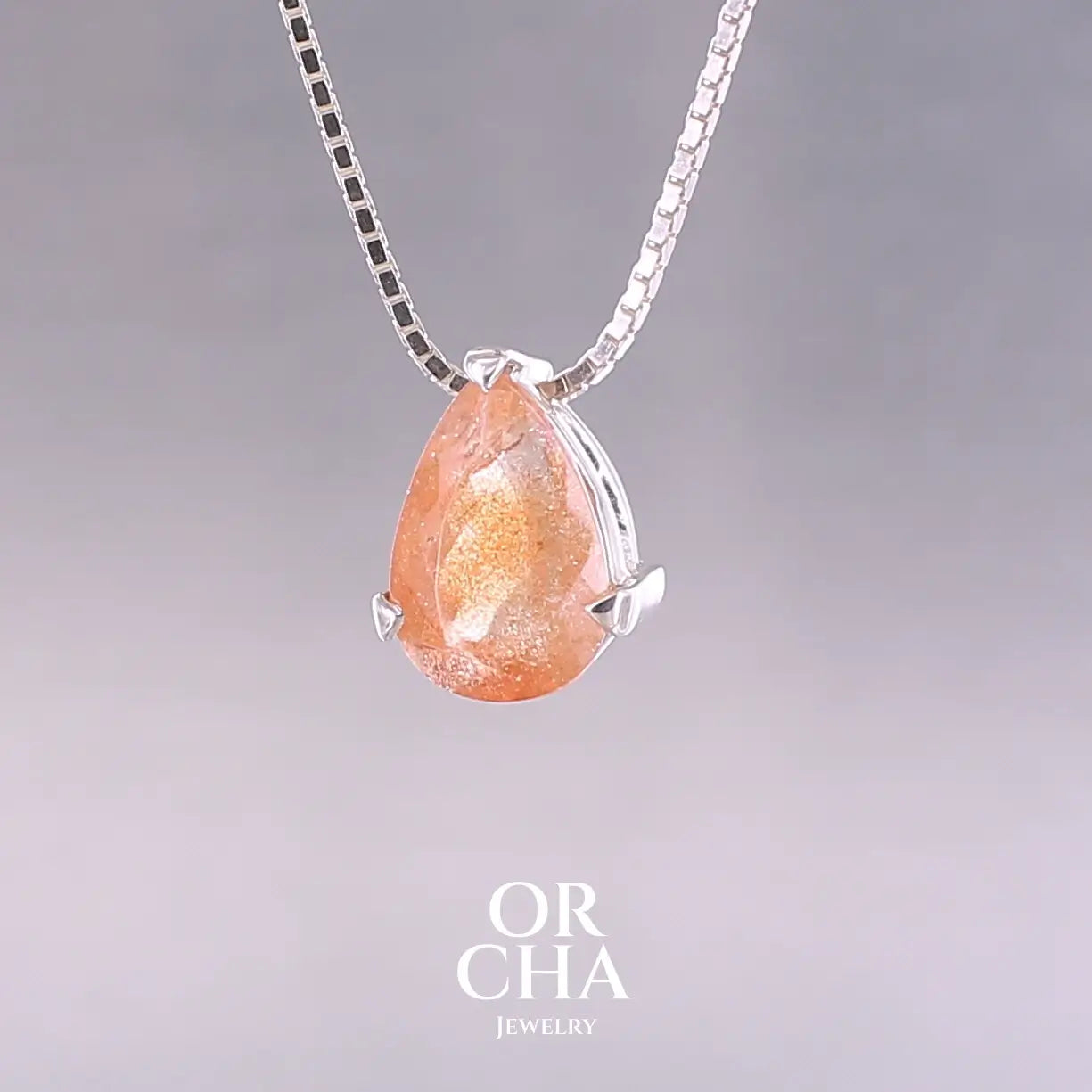 Collier solitaire pour femme en argent massif serti d'une pierre de soleil. Pierre de couleur orange facettée en forme de goutte, qualité transparente à  inclusions scintillantes dorées orangées. Pendentif monté sur une chaine en argent sterling de type maille carrée miroir de 0,94 mm d'épaisseur et de 40 cm de longueur. Bijoux unique, éthique et durable présenté dans un coffret de notre marque, prêt à offrir. Livraison offerte, certificat d'authenticité, service client.