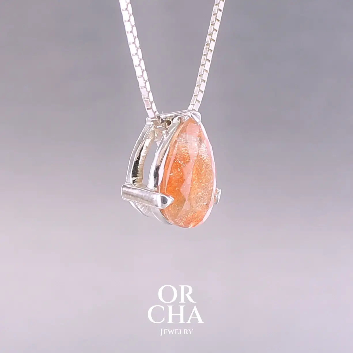 Collier solitaire pour femme en argent massif serti d'une pierre de soleil. Pierre de couleur orange facettée en forme de goutte, qualité transparente à  inclusions scintillantes dorées orangées. Pendentif monté sur une chaine en argent sterling de type maille carrée miroir de 0,94 mm d'épaisseur et de 40 cm de longueur. Bijoux unique, éthique et durable présenté dans un coffret de notre marque, prêt à offrir. Livraison offerte, certificat d'authenticité, service client.