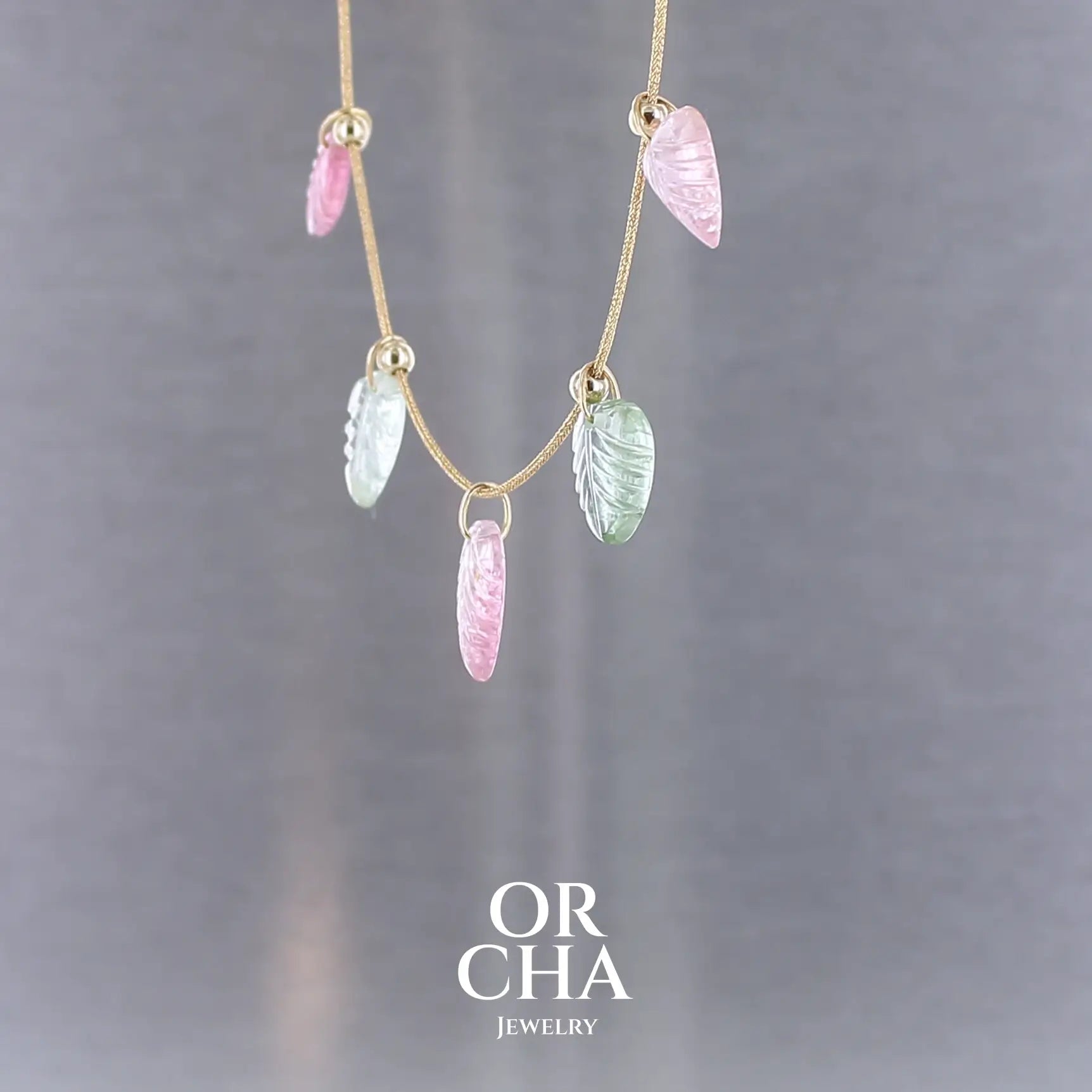 Collier pour femme orné de tourmalines roses et vertes sculptées à la main en 3 dimensions en forme de feuilles serties en or 18k. Les breloques sont montées sur un collier corde doré scintillant, les apprêts utilisé sont en Gold filled ( or laminé ). Longueur ajustable de 40 cm à 45 cm. Bijoux unique, éthique et durable présenté dans un coffret de notre marque, prêt à offrir. Livraison offerte, certificat d'authenticité, service client.